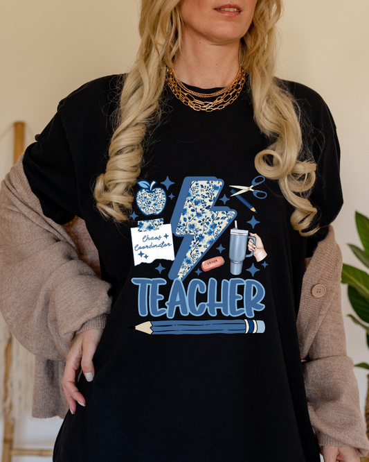 Person wearing a black t-shirt with blue graphics and text, standing indoors.