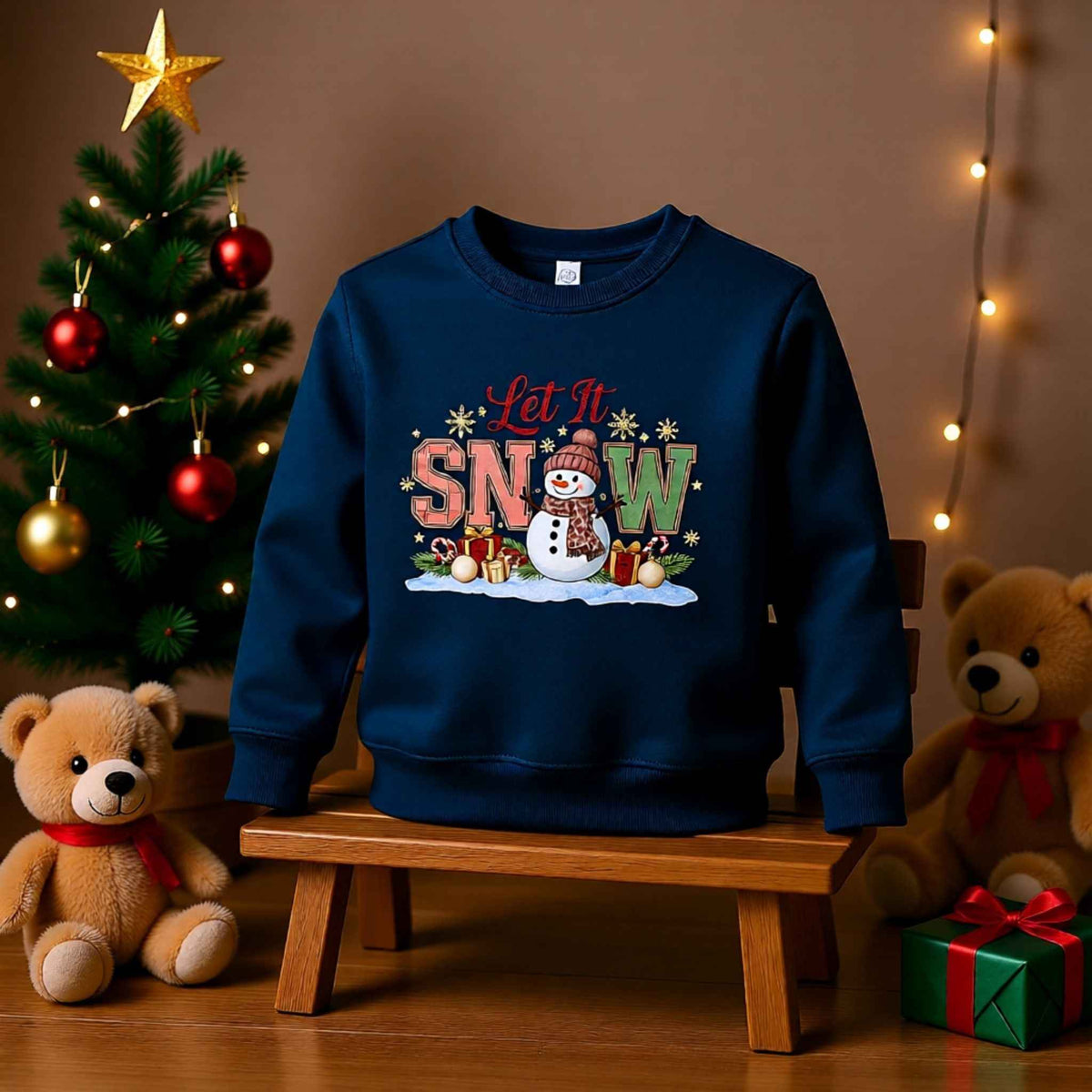 Toddler “Let It Snow” Christmas crewneck sweatshirt with snowman design, displayed with festive holiday decor and teddy bears.