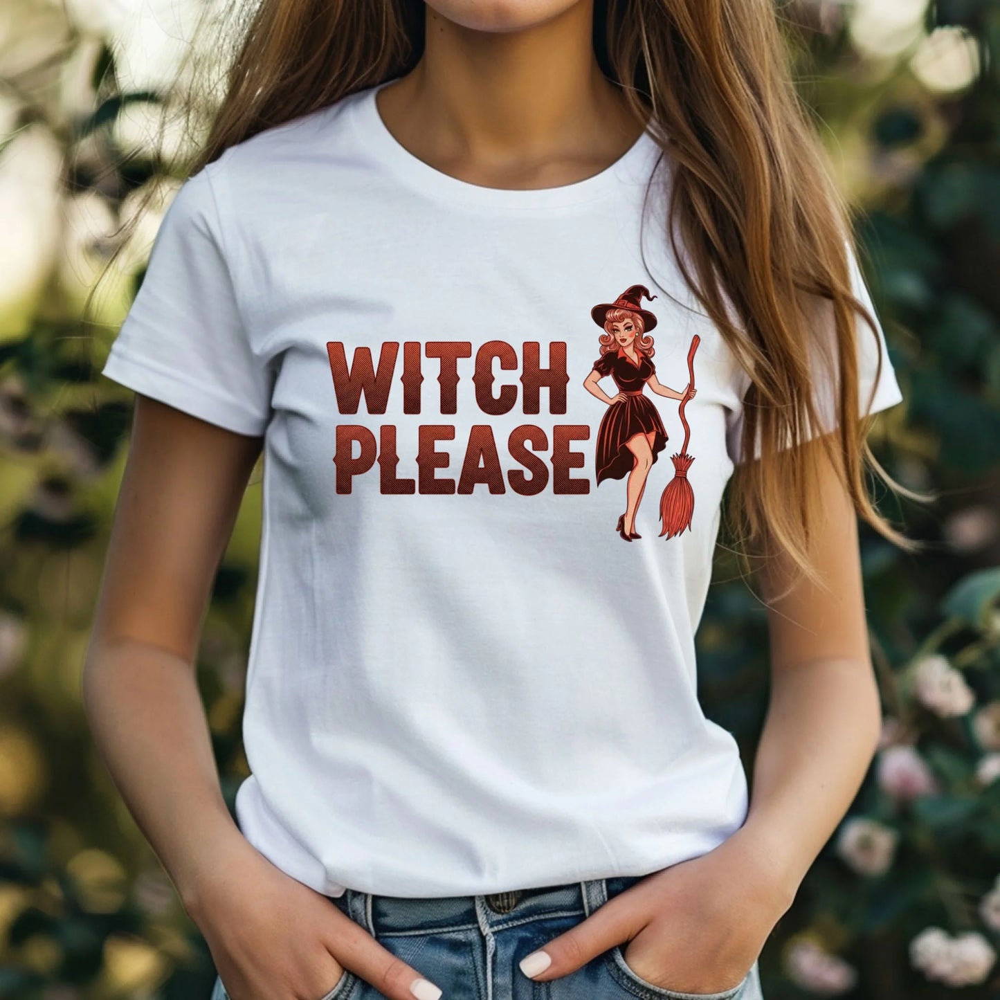 Person wearing a white t-shirt with 'Witch Please' graphic design outdoors.