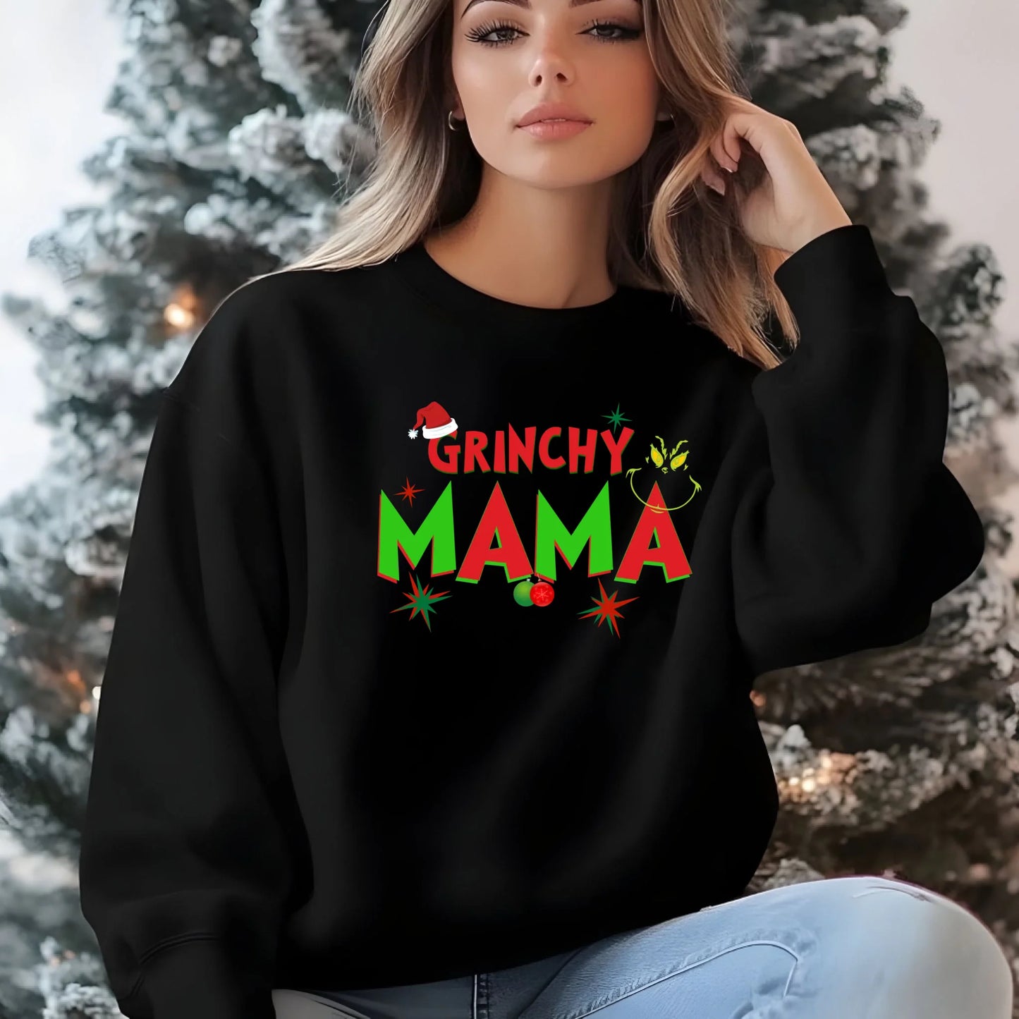 Woman wearing a black sweatshirt with 'Grinchy Mama' text in front of a decorated Christmas tree.