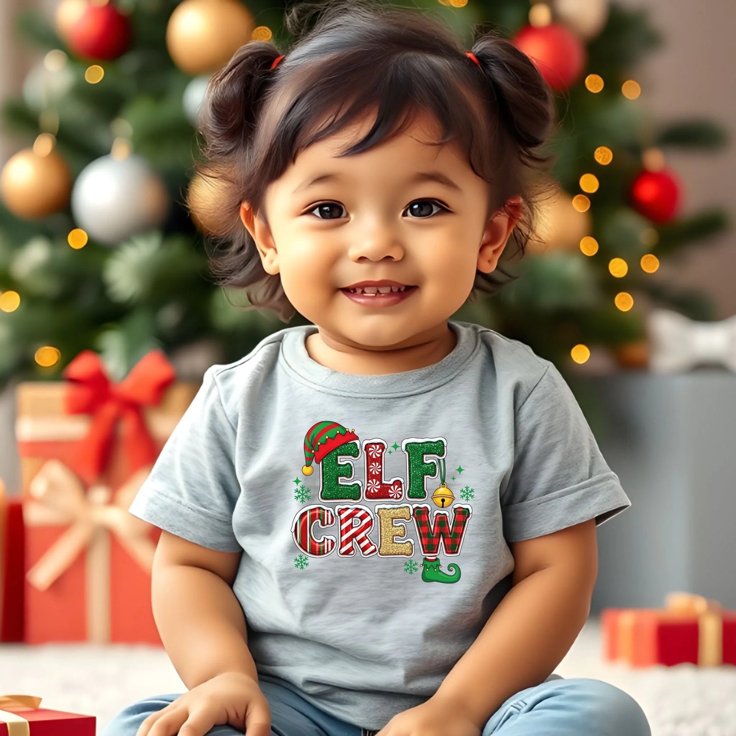 Child wearing a 'Elf Crew' shirt in front of a decorated Christmas tree with presents.