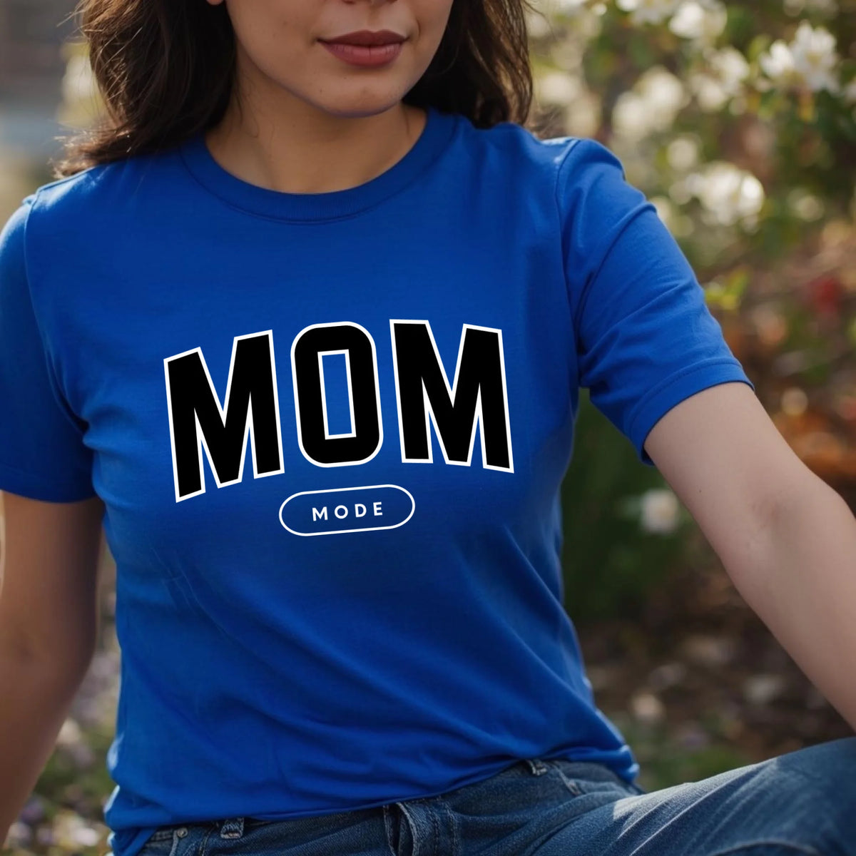 Person wearing a blue t-shirt with 'MOM MODE' text outdoors.