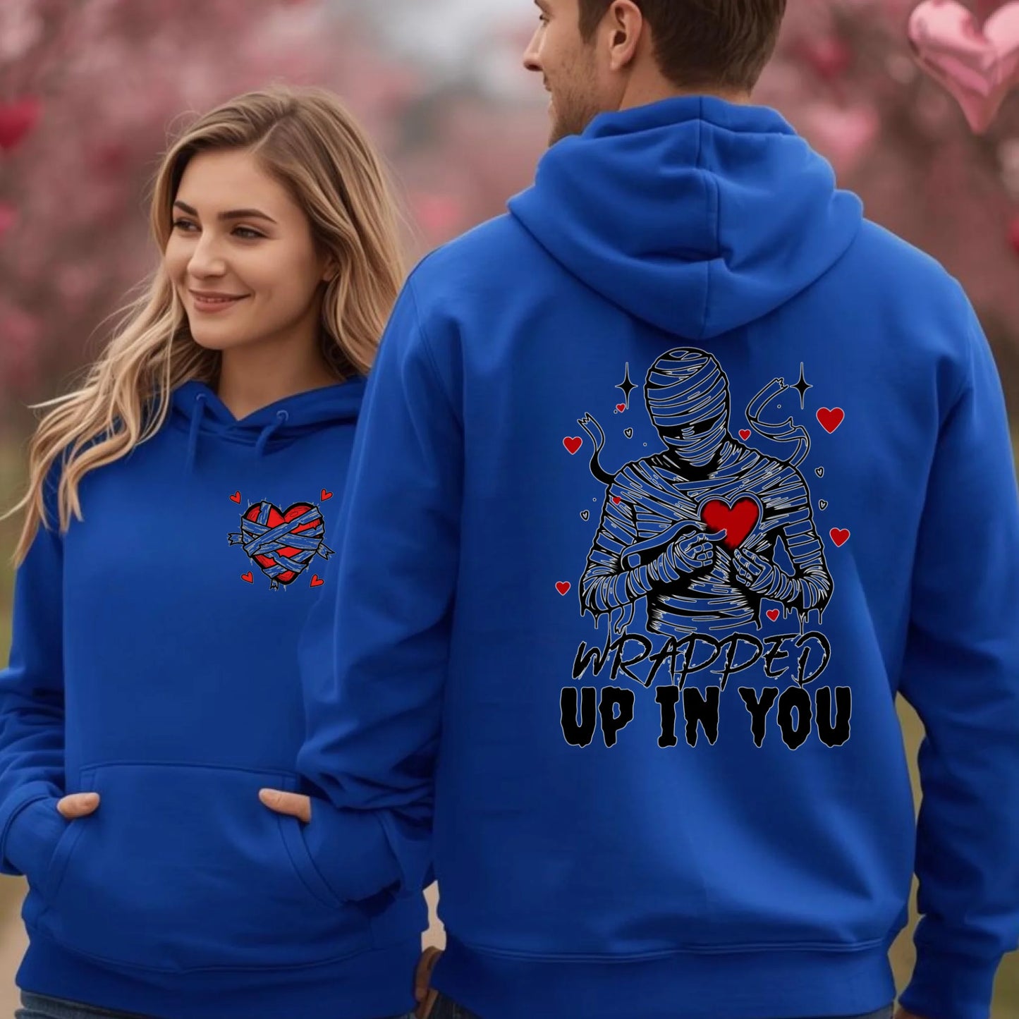 Two people wearing blue hoodies with heart-themed designs, one on the front and one on the back.