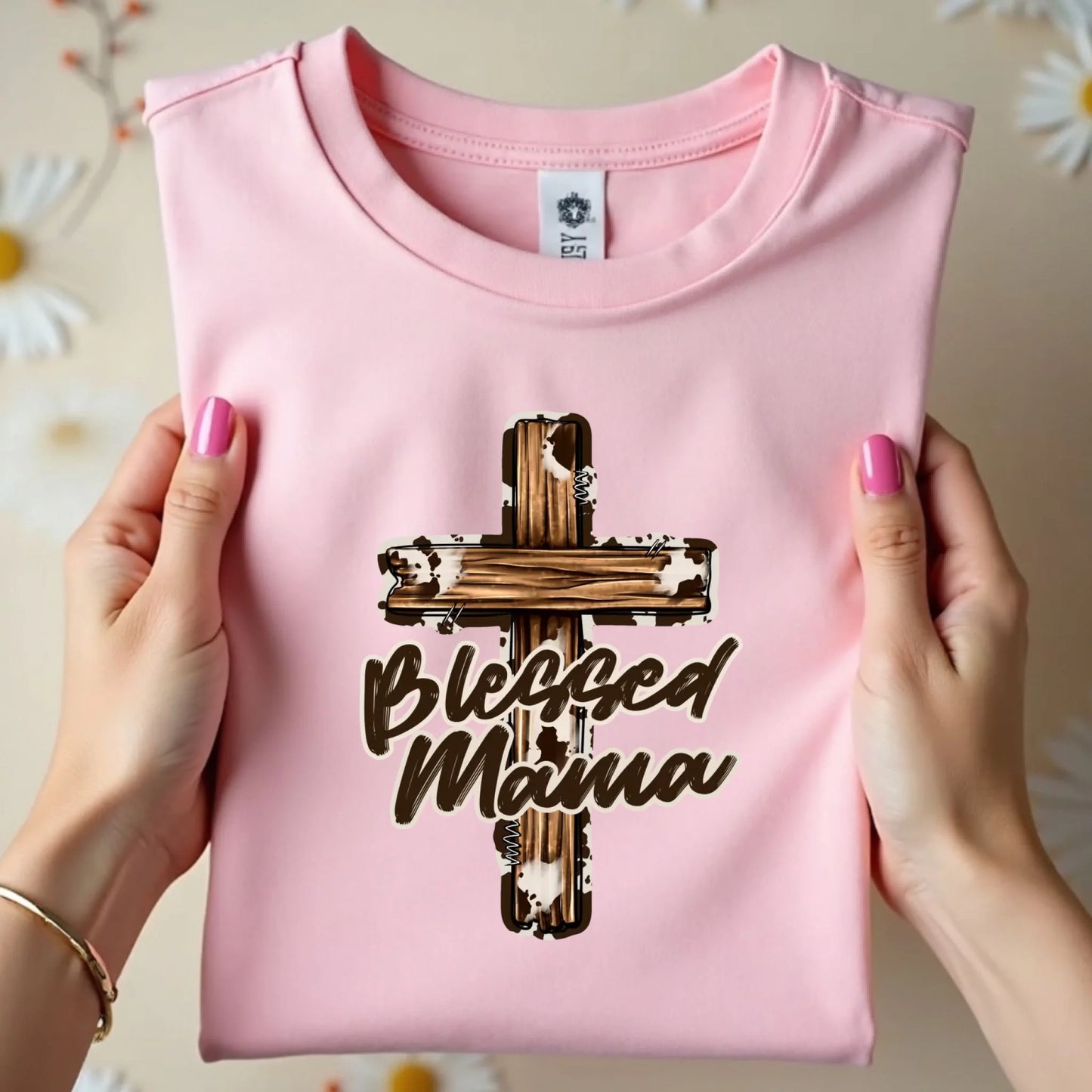 Flat lay of a pink Bella Canvas Blessed Mama cross t-shirt neatly folded, showcasing the front design and print quality.