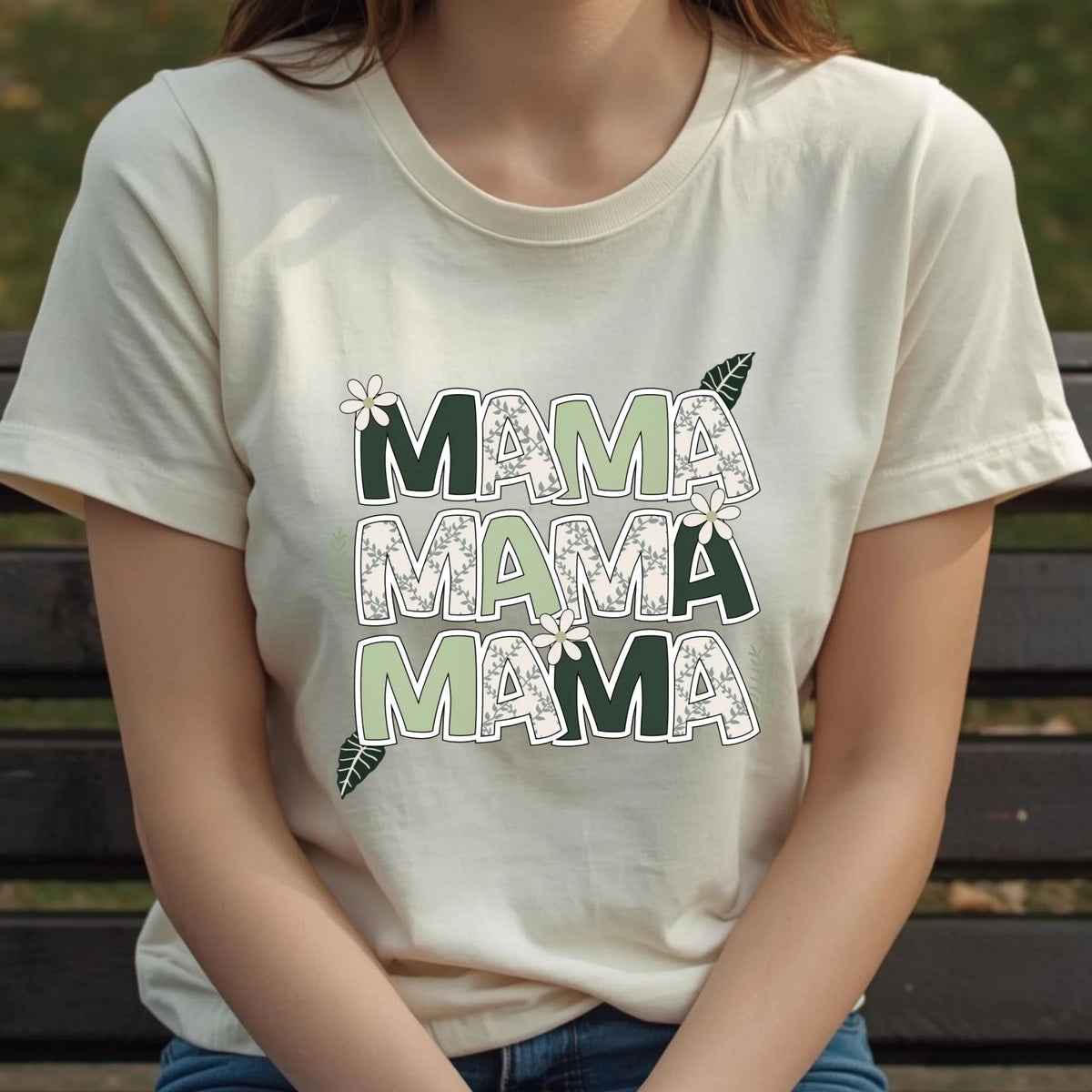 Torso view of a woman wearing a cream floral “Mama” t-shirt with soft botanical lettering.