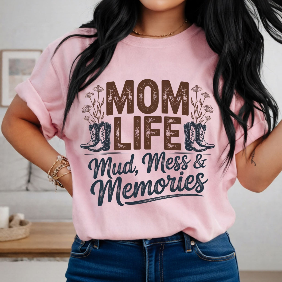 Person wearing a pink t-shirt with 'Mom Life: Mud, Mess & Memories' text and boot graphics.