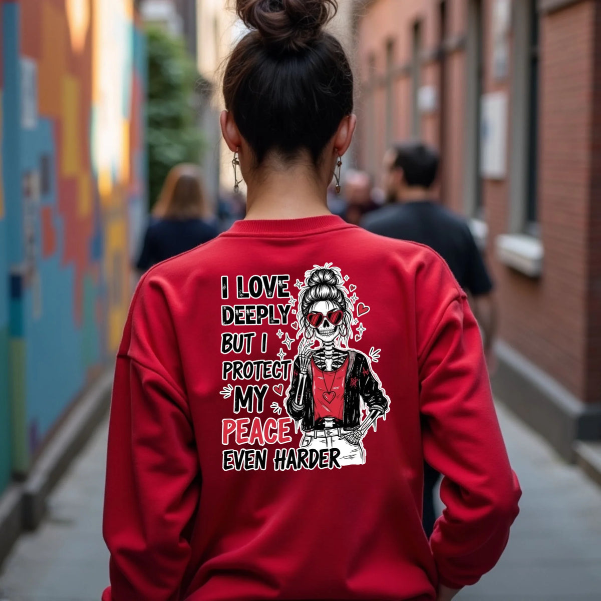 Red Gildan crewneck with “Love Hard Heal Harder” skeleton graphic printed on the back, modeled outdoors in a casual real-life setting.
