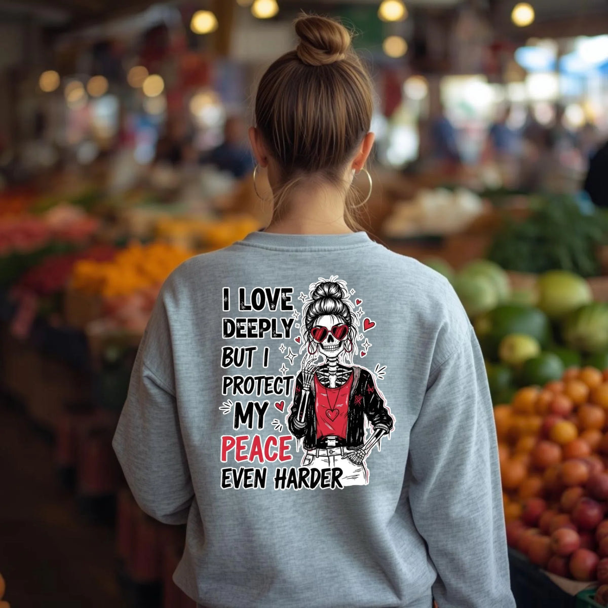 Sport grey crewneck featuring “Love Hard Heal Harder” back design, worn casually while shopping at an outdoor market.