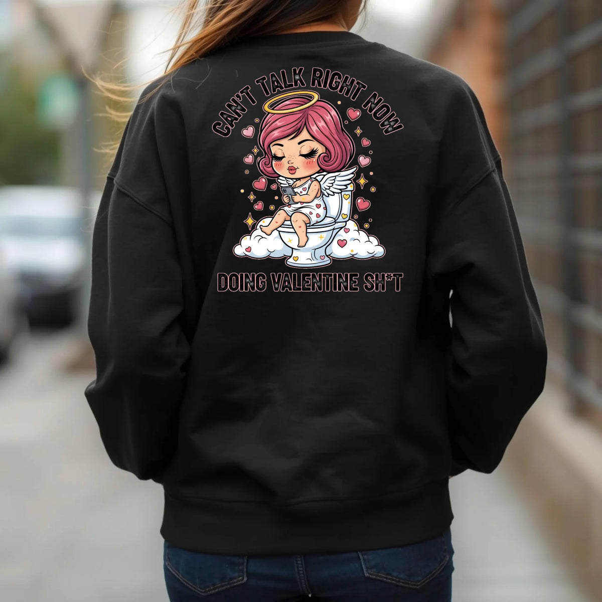 Person wearing a black crewneck sweatshirt with a graphic design on the back, featuring a humorous Toilet Cupid Valentine graphic.