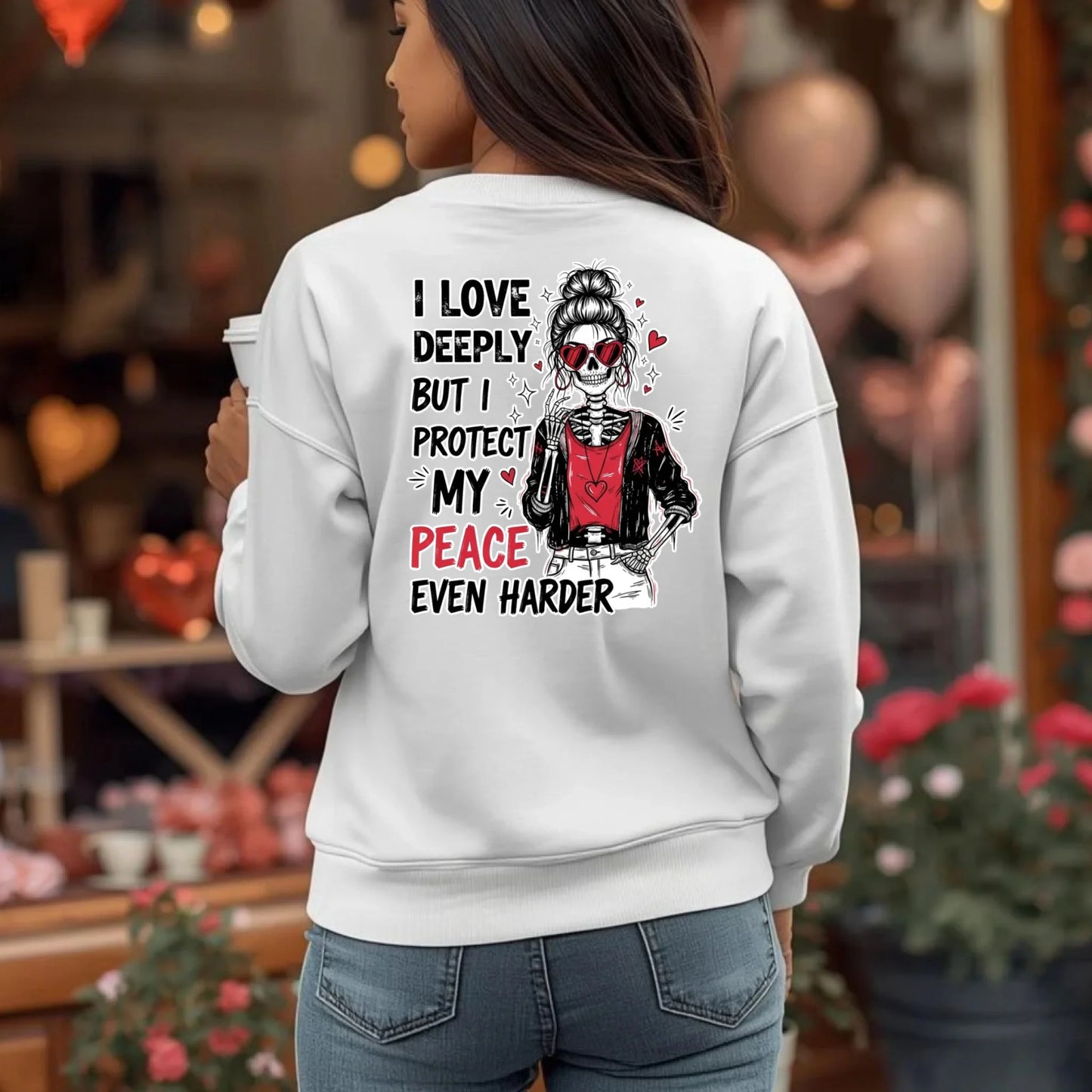 White crewneck sweatshirt with skeleton and heart themed back print, woman covered from behind in everyday environment.