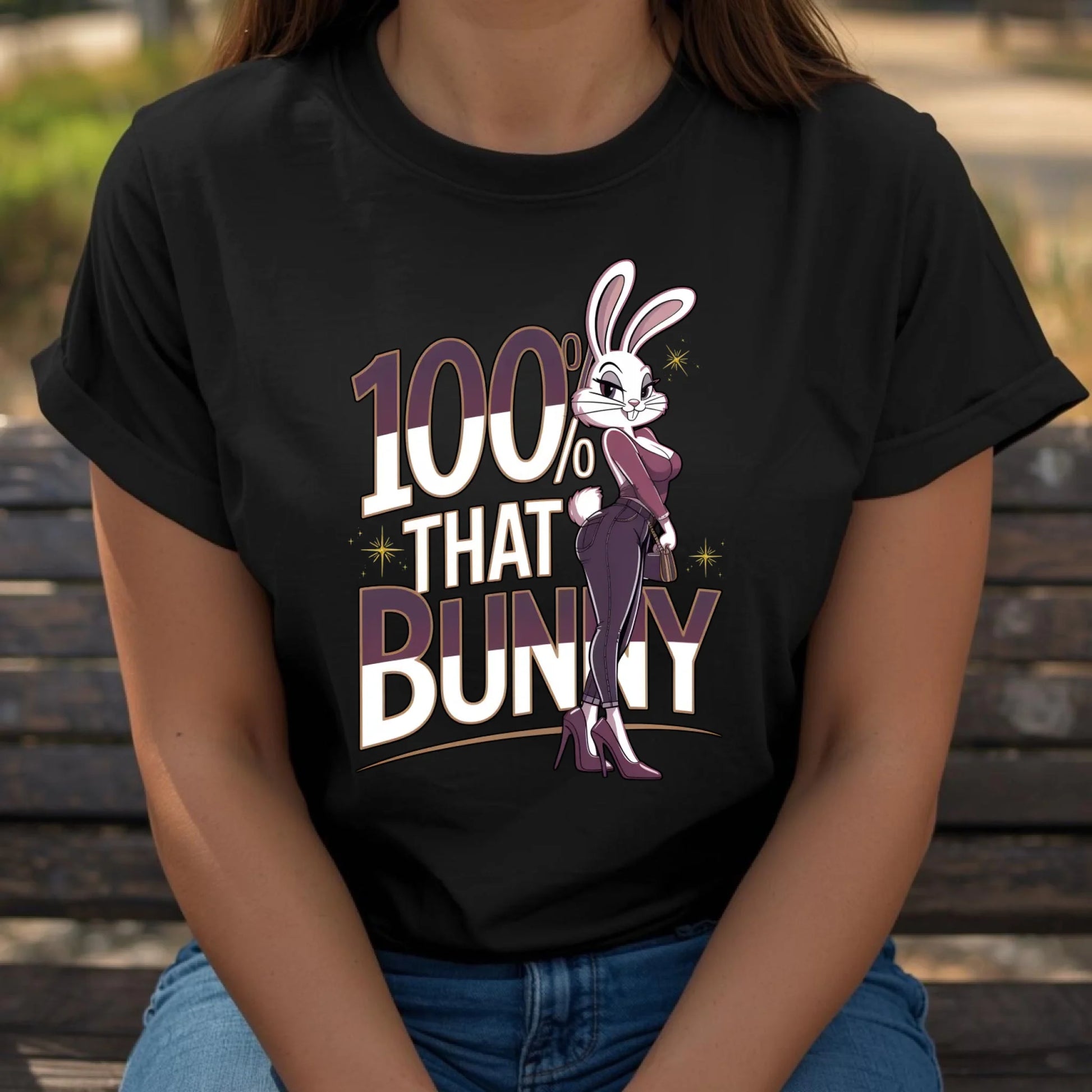 Woman seated casually wearing a black Bella + Canvas t-shirt featuring the 100% That Bunny Easter graphic. Relaxed lifestyle pose showcasing a confident, trendy bunny design perfect for spring outfits.