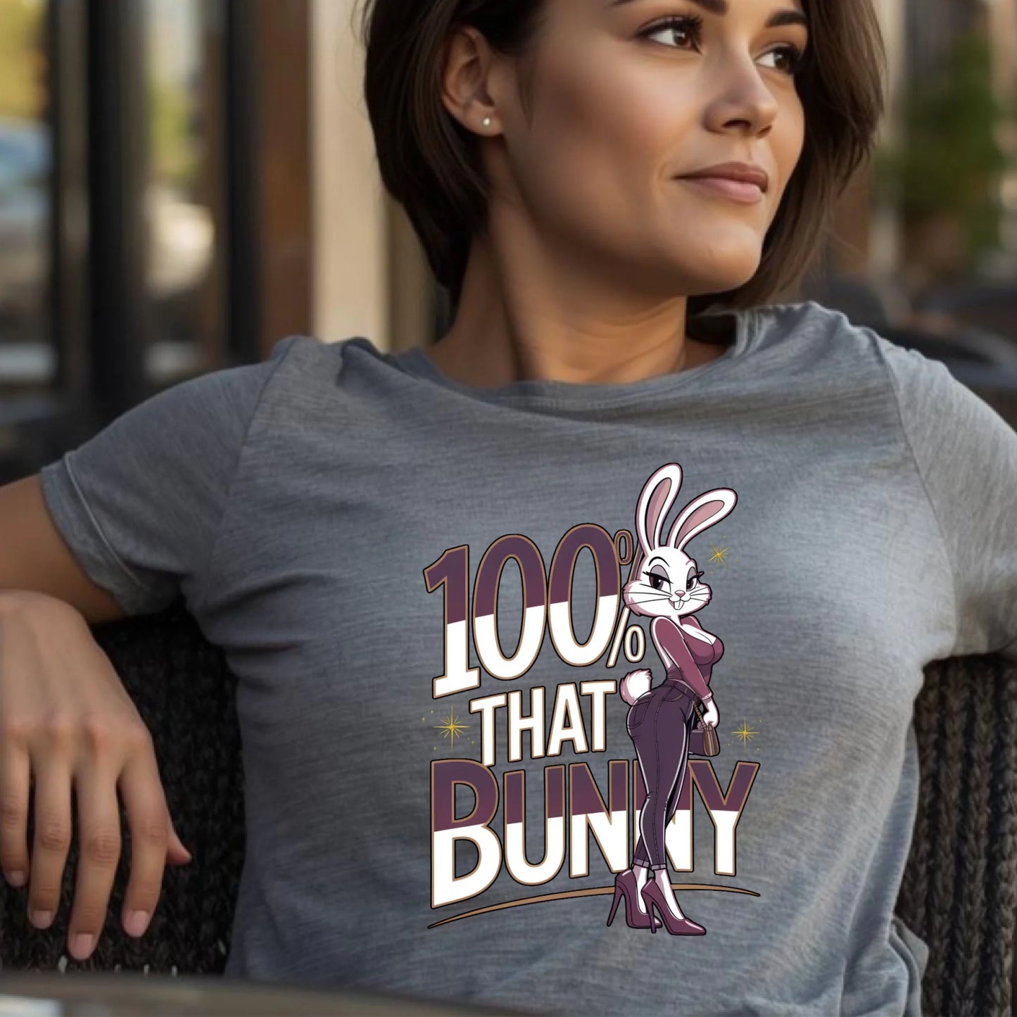 Woman wearing a heather gray Bella + Canvas t-shirt featuring the 100% That Bunny Easter graphic. Confident side pose in a lifestyle setting, highlighting a bold and stylish spring bunny design.