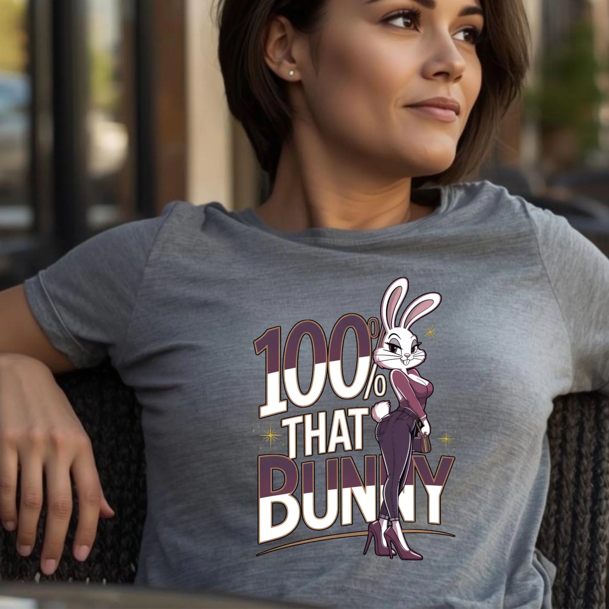 Woman wearing a heather gray Bella + Canvas t-shirt featuring the 100% That Bunny Easter graphic. Confident side pose in a lifestyle setting, highlighting a bold and stylish spring bunny design.