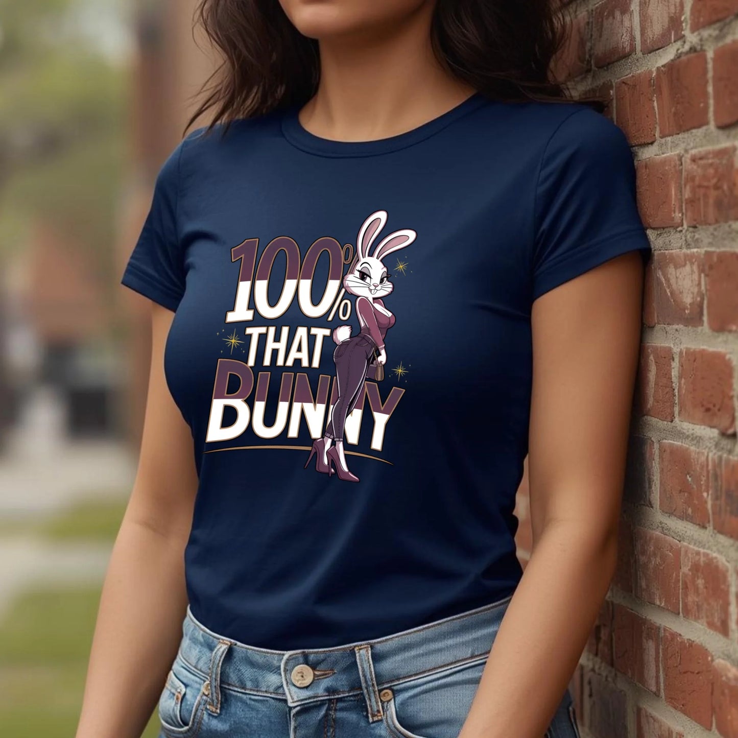 Woman leaning casually against a brick wall wearing a navy Bella + Canvas t-shirt with the 100% That Bunny confident Easter design. Urban spring styling with a modern, fashion-forward vibe.