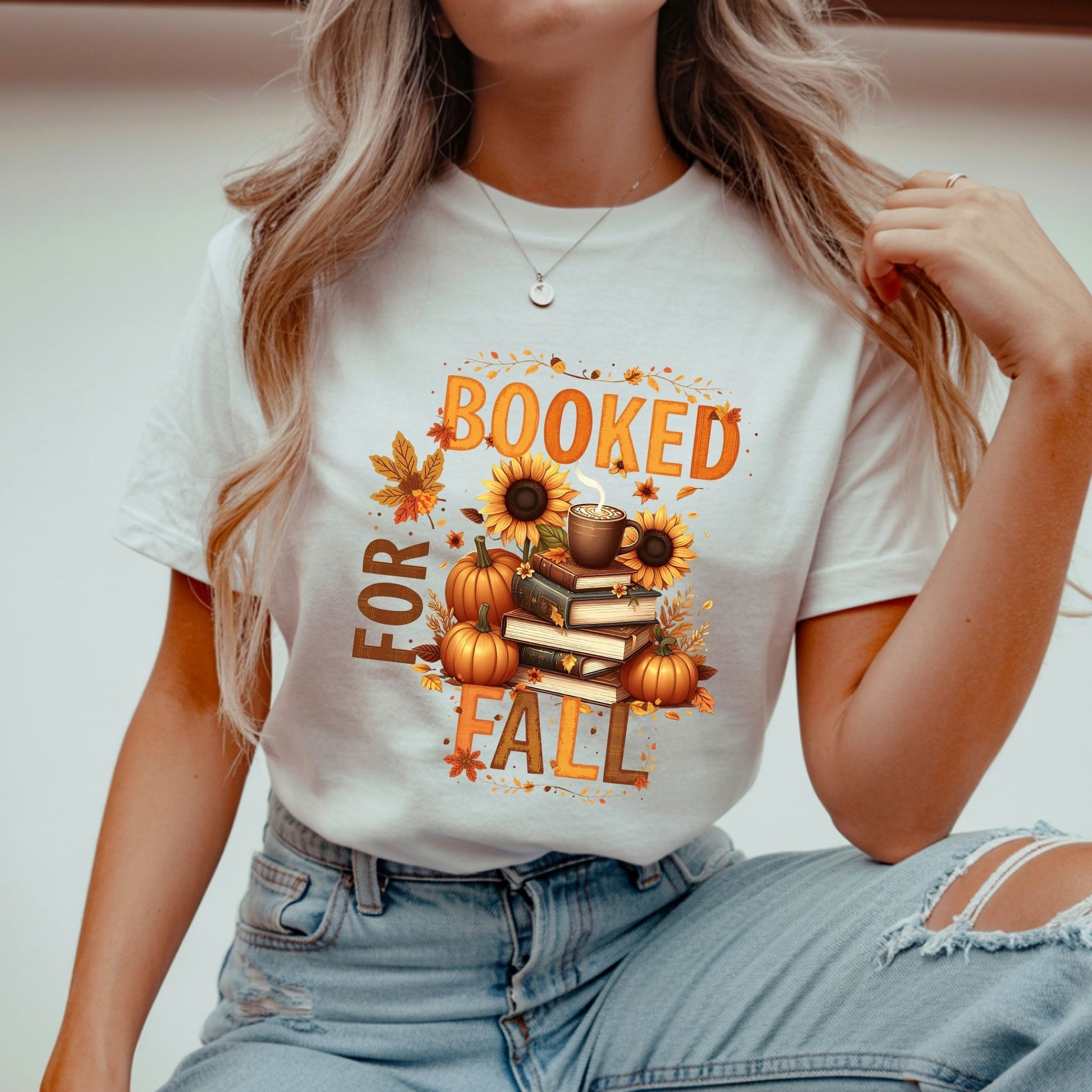 Person wearing a white t-shirt with 'Booked for Fall' design featuring pumpkins, books, and sunflowers.