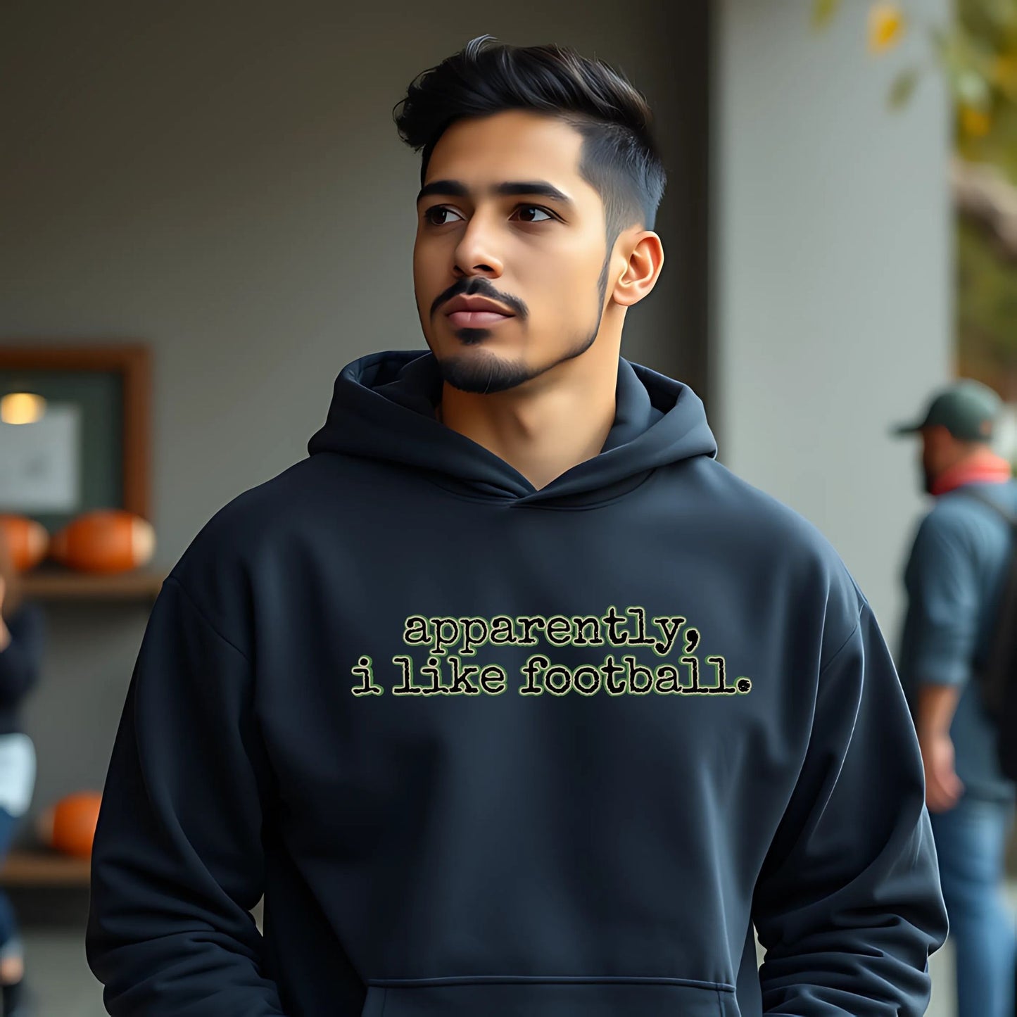 Man wearing a hoodie with text 'apparently, i like football.' in an indoor setting.