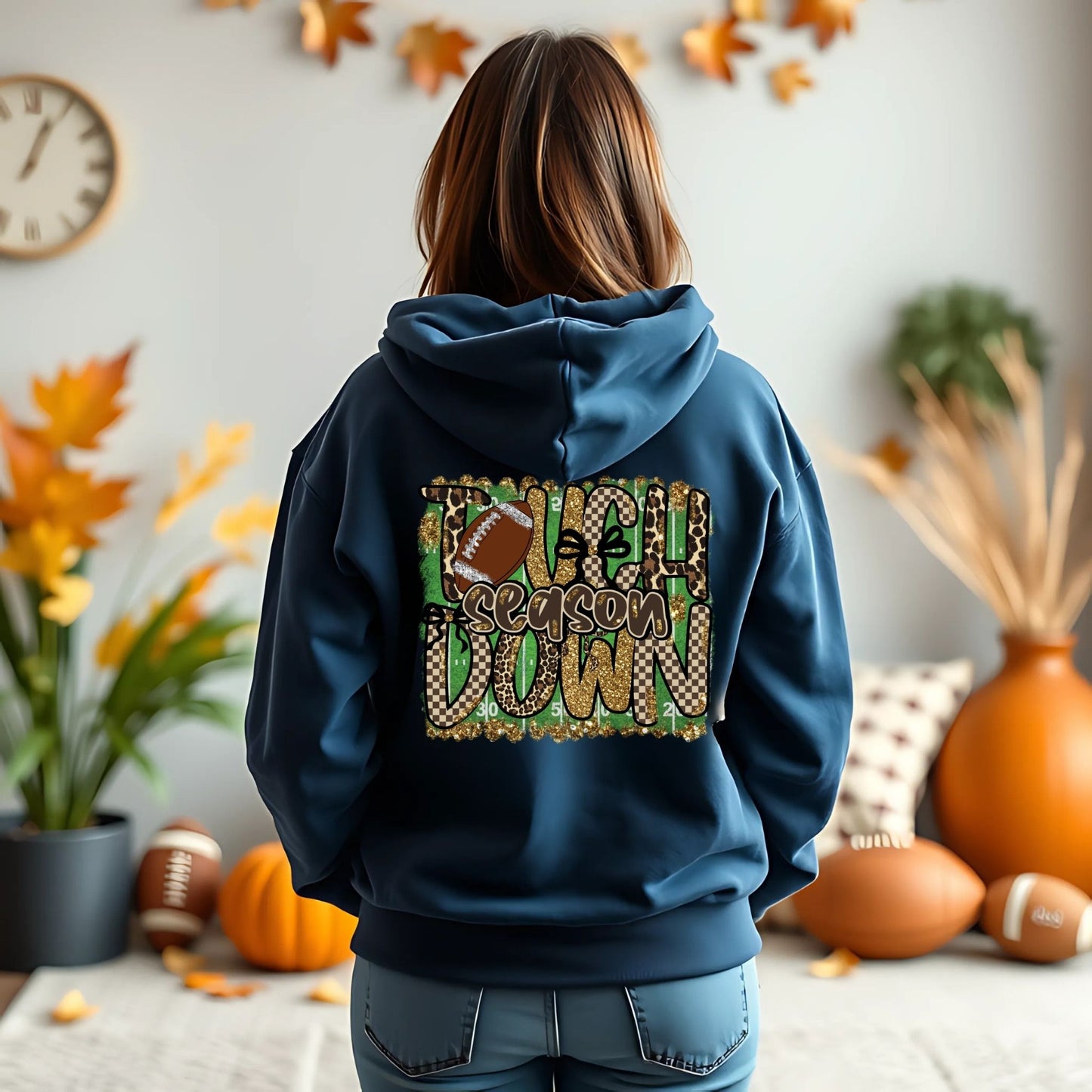Person wearing a blue hoodie with 'Touchdown Season' design in a room decorated for fall.