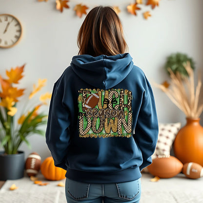 Person wearing a blue hoodie with 'Touchdown Season' design in a room decorated for fall.