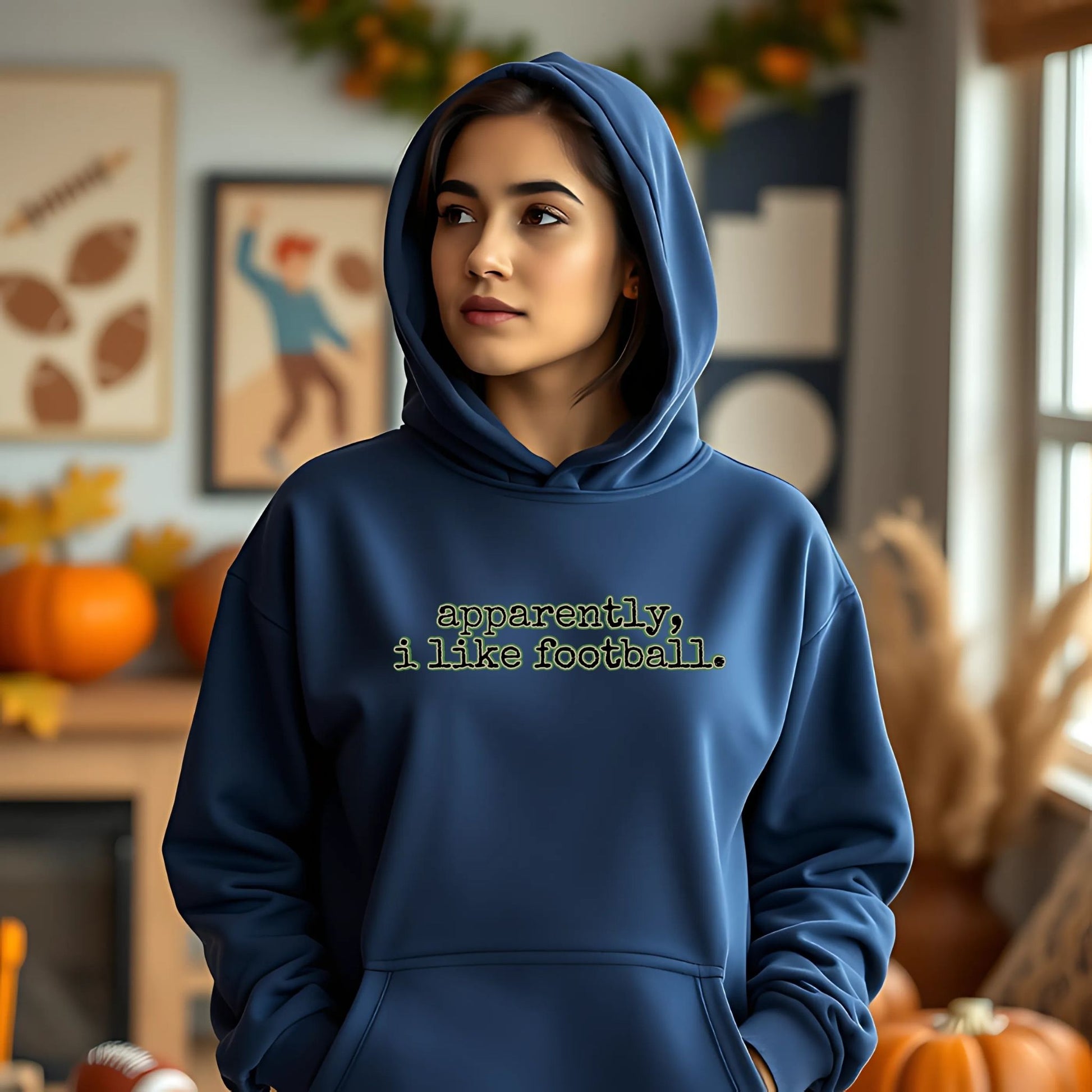 Person wearing a blue hoodie with text in a cozy room with autumn decorations.