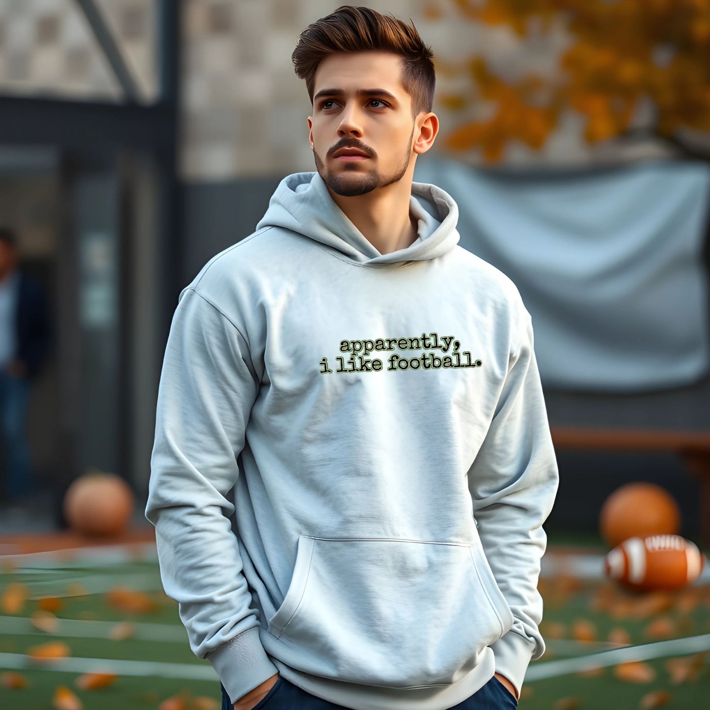Man wearing a hoodie with 'apparently, i like football' text on a sports field.