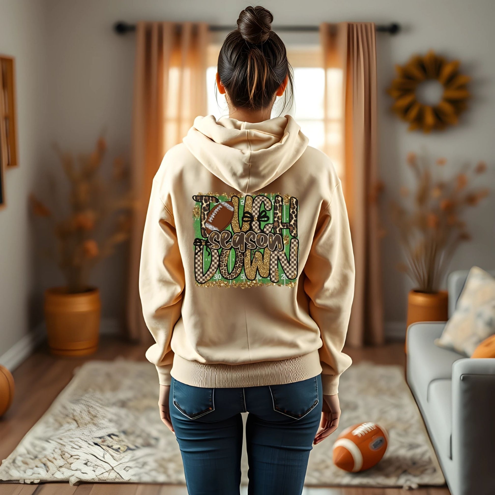 Person wearing a beige hoodie with text and graphics in a living room.