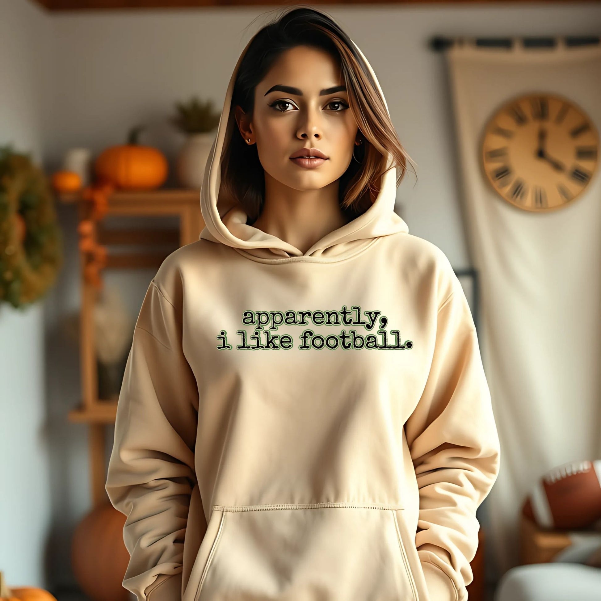 Woman wearing a beige hoodie with text in a cozy indoor setting