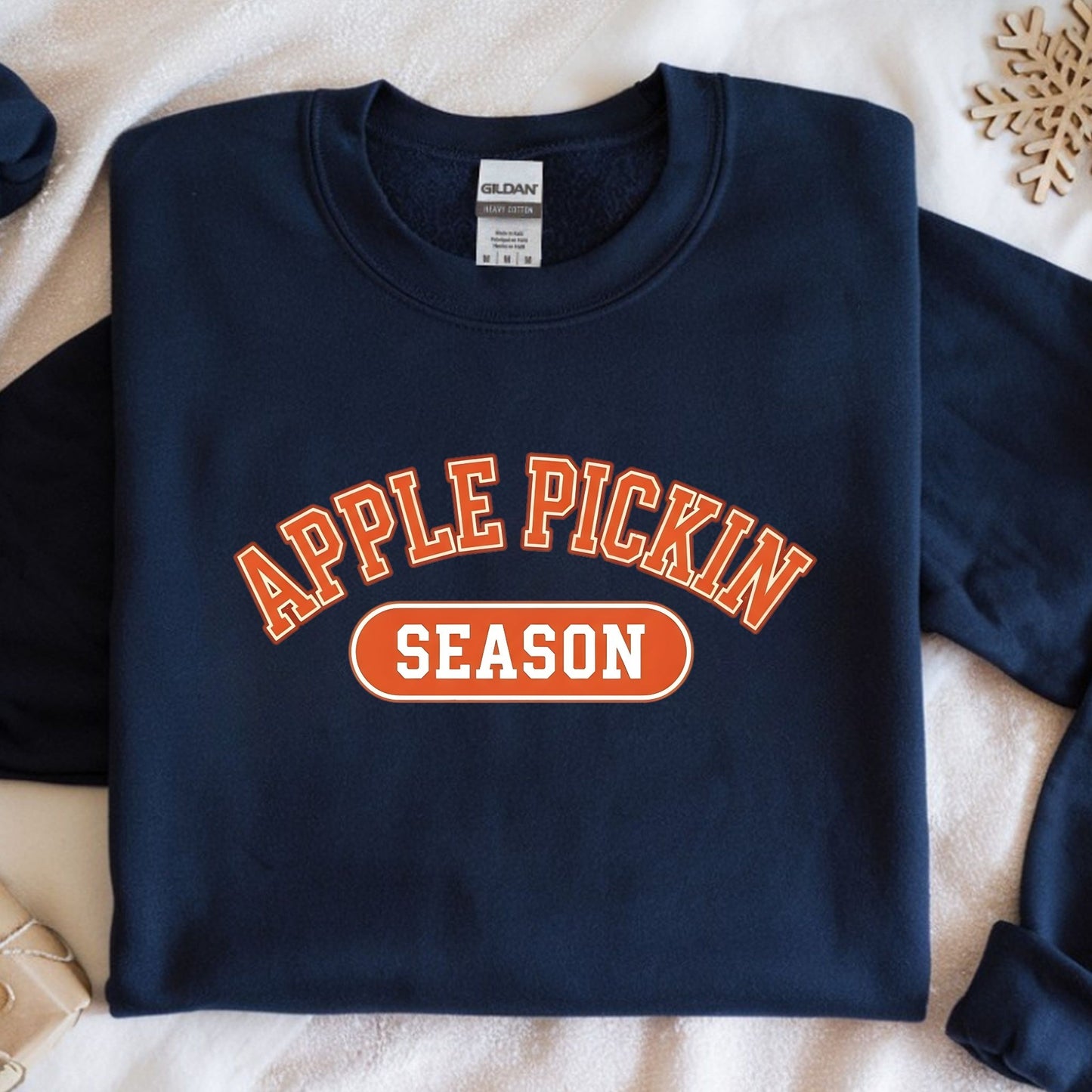 Navy blue sweatshirt with 'Apple Pickin' Season' text on a beige surface