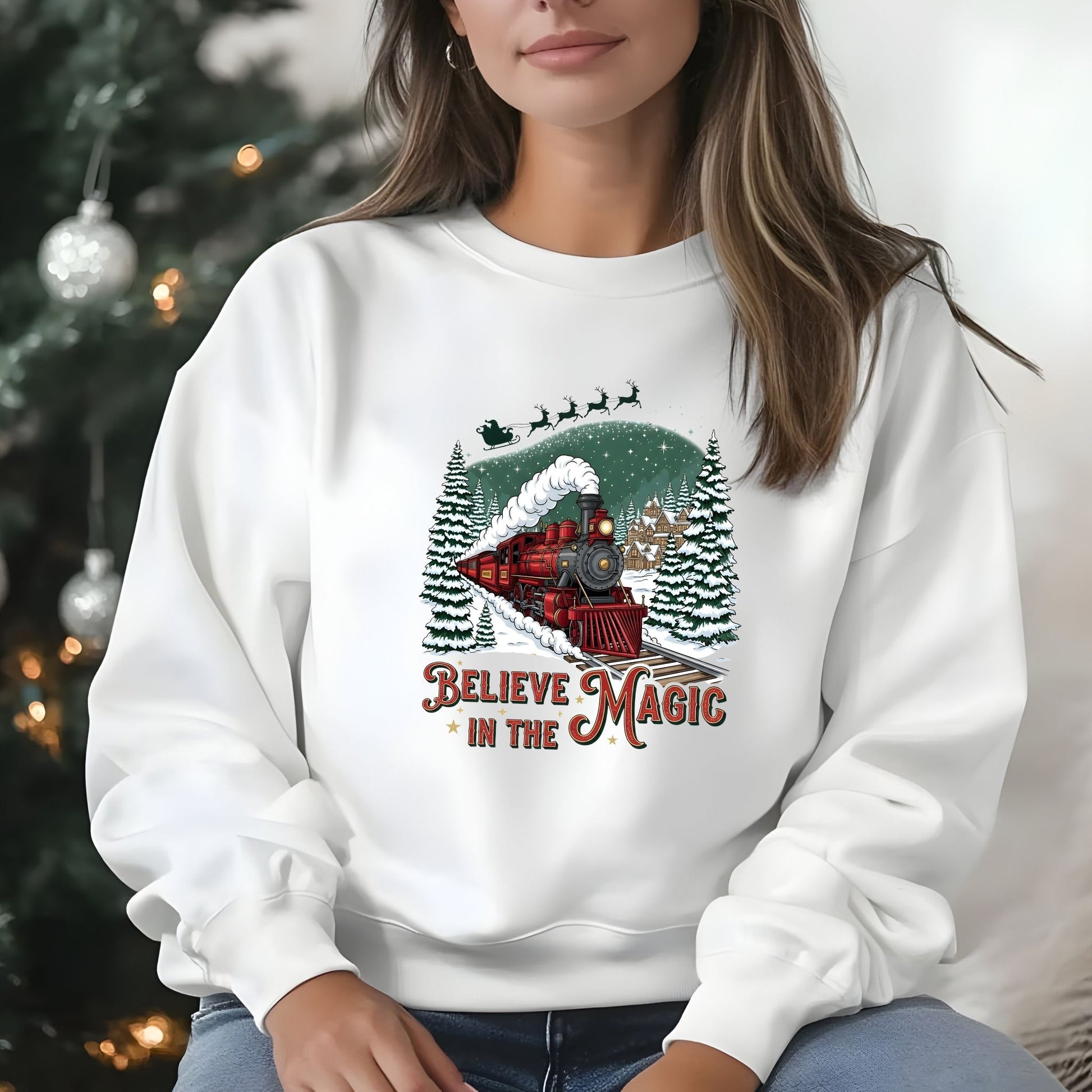 Person wearing a white sweatshirt with a Christmas-themed design and text, sitting in front of a decorated tree.