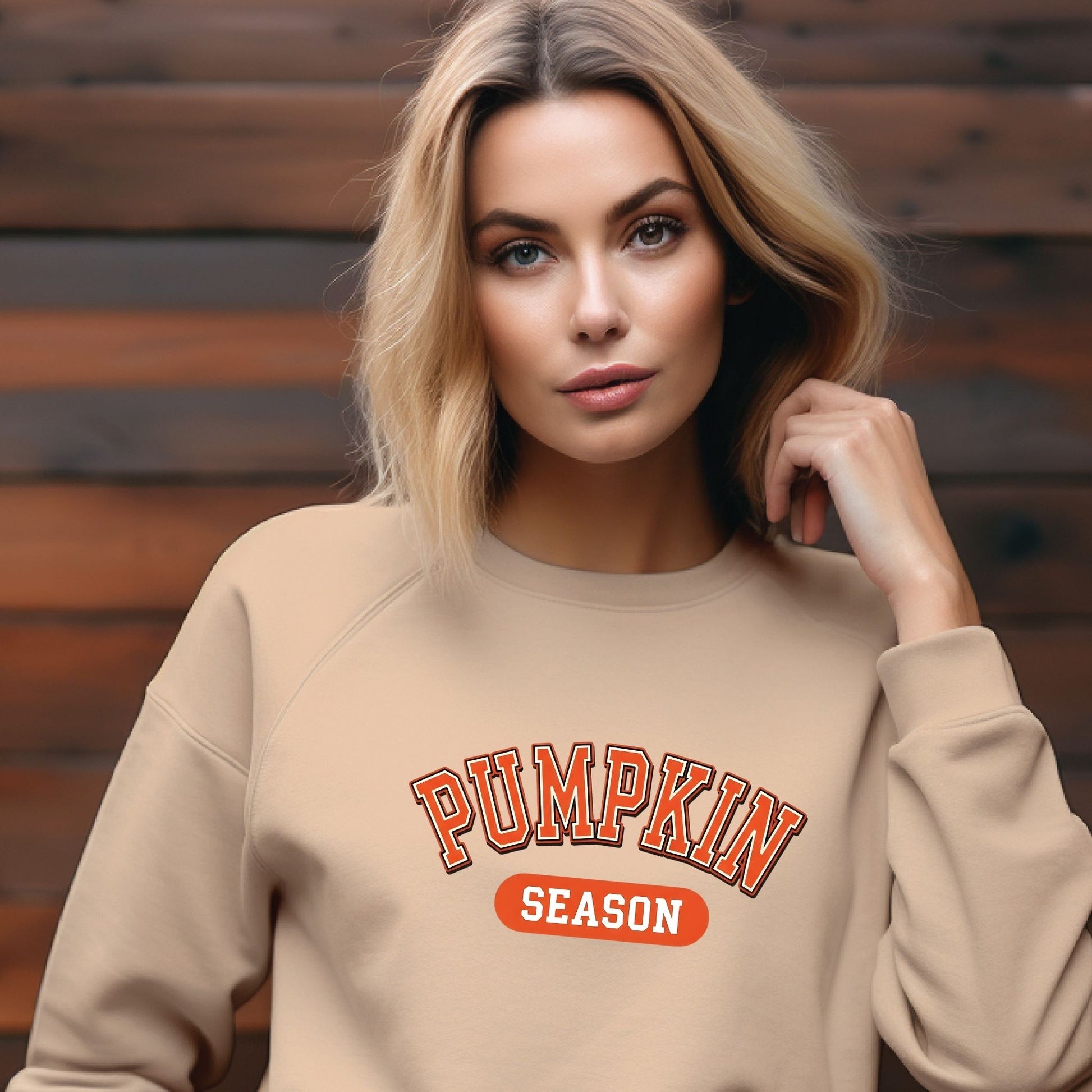 Woman wearing a beige sweatshirt with 'Pumpkin Season' text against a wooden background
