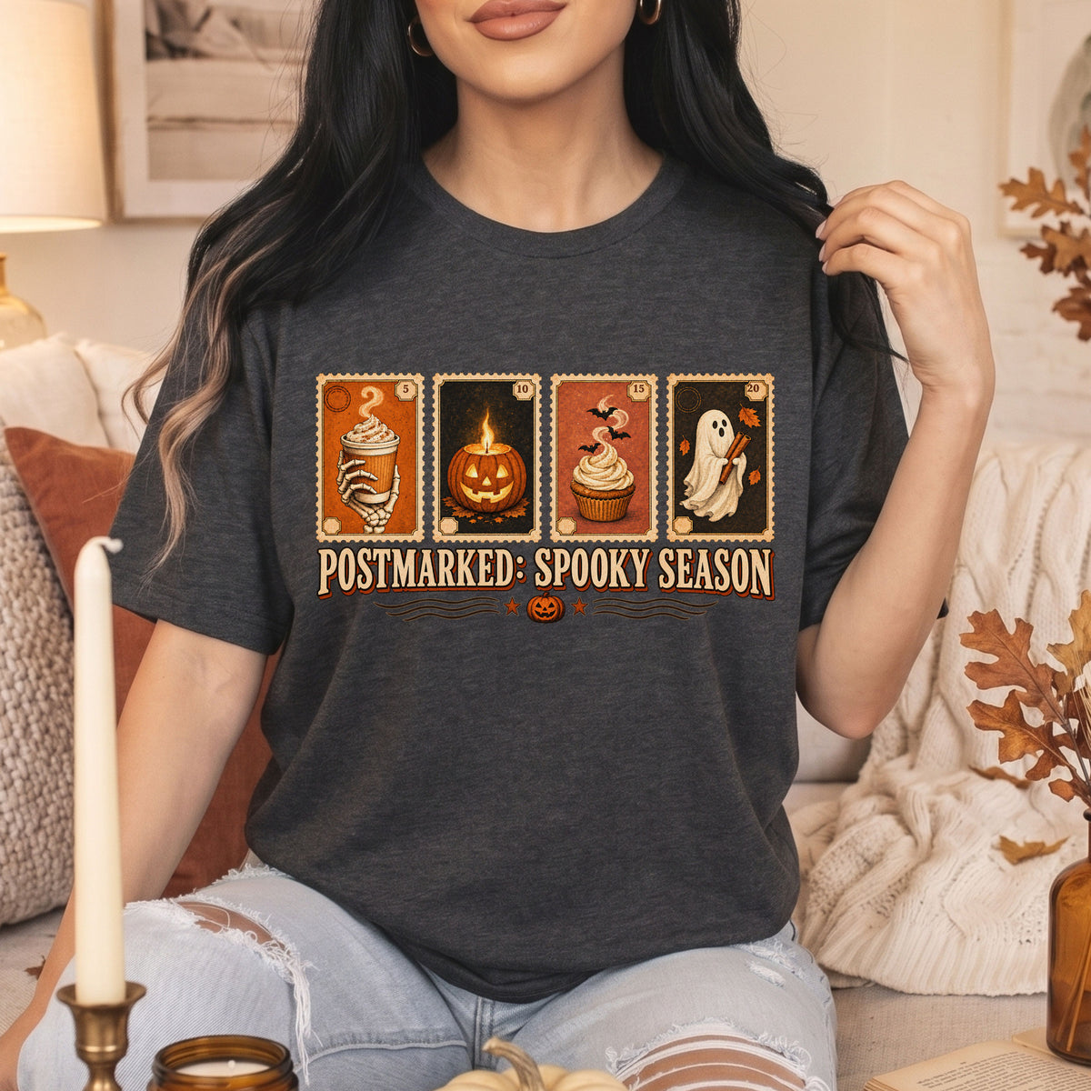 A woman wearing a dark gray heather graphic t-shirt with Halloween-themed illustrations and the text 'POSTMARKED: SPOOKY SEASON'.