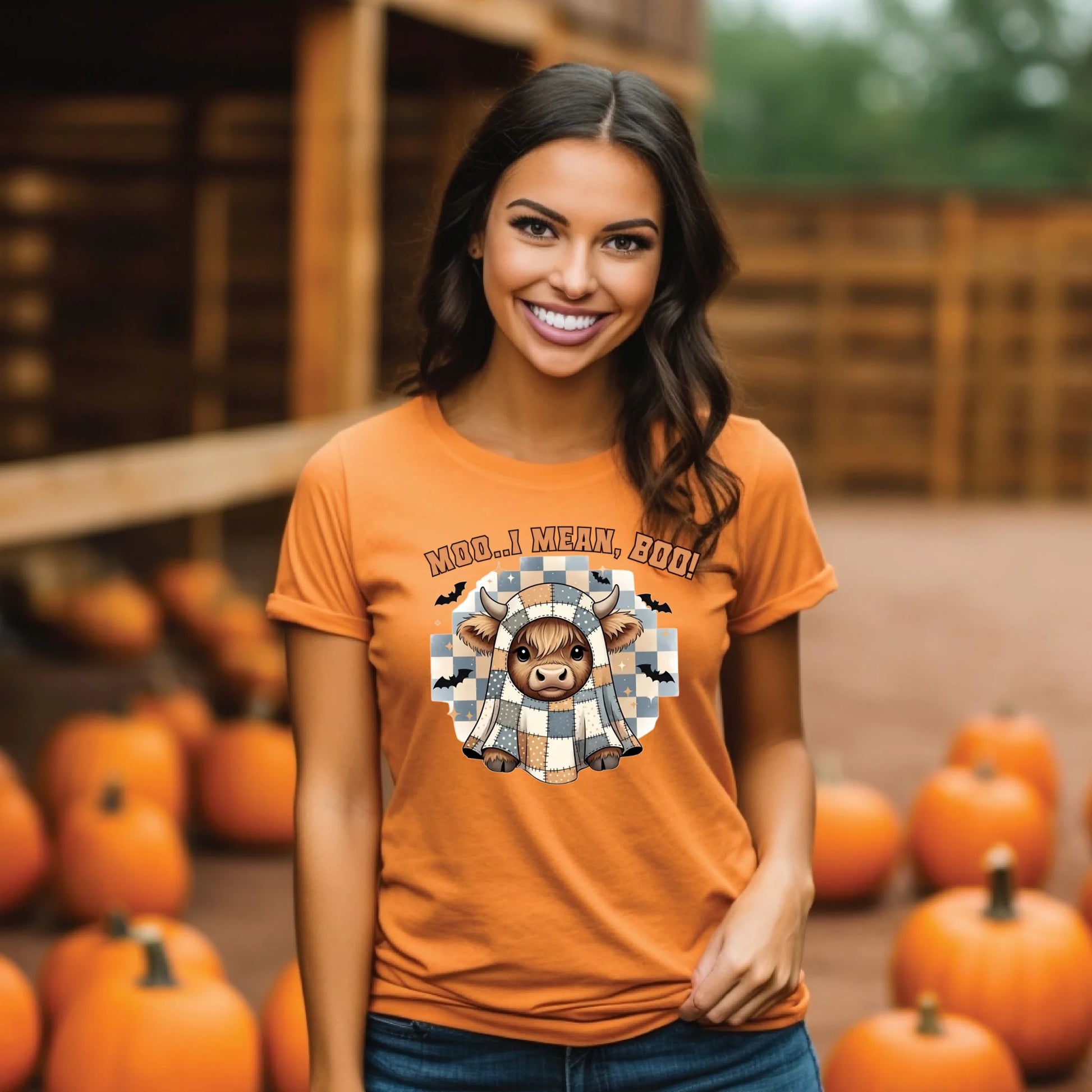 Woman wearing an orange t-shirt with a graphic design of a cow in a checkered shirt and text 'MOO.