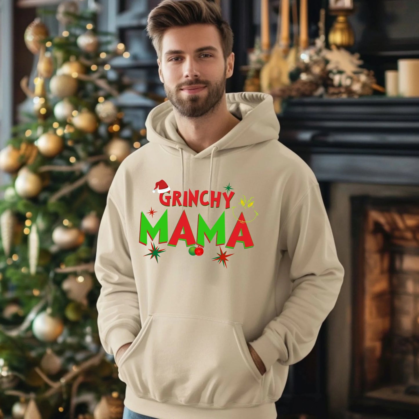 Man wearing a 'Grinchy Mama' hoodie in front of a decorated Christmas tree.