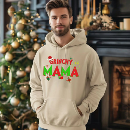 Man wearing a 'Grinchy Mama' hoodie in front of a decorated Christmas tree.