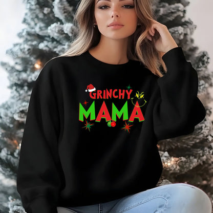 Woman wearing a black sweatshirt with 'Grinchy Mama' text in front of a decorated Christmas tree.