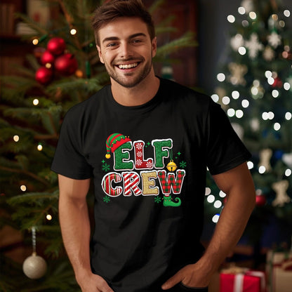Man wearing a black t-shirt with 'Elf Crew' design in front of Christmas trees.