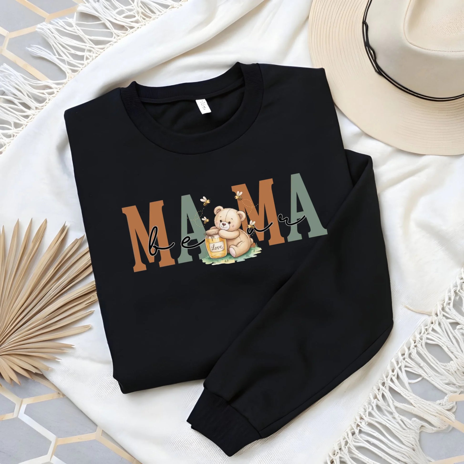 Flat lay image of a black personalized mama crewneck highlighting the honey bear artwork and premium print quality.