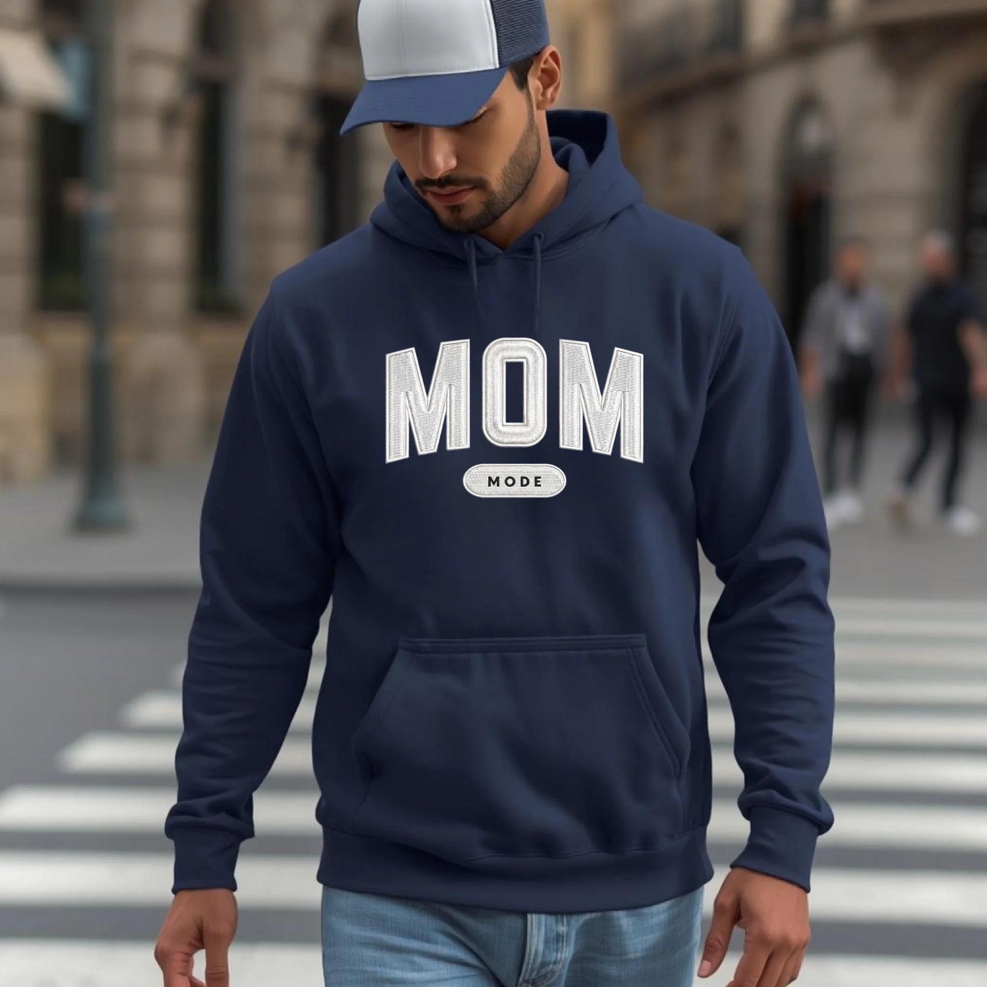 Man wearing a navy hoodie with 'DAD MODE' text on a city street.
