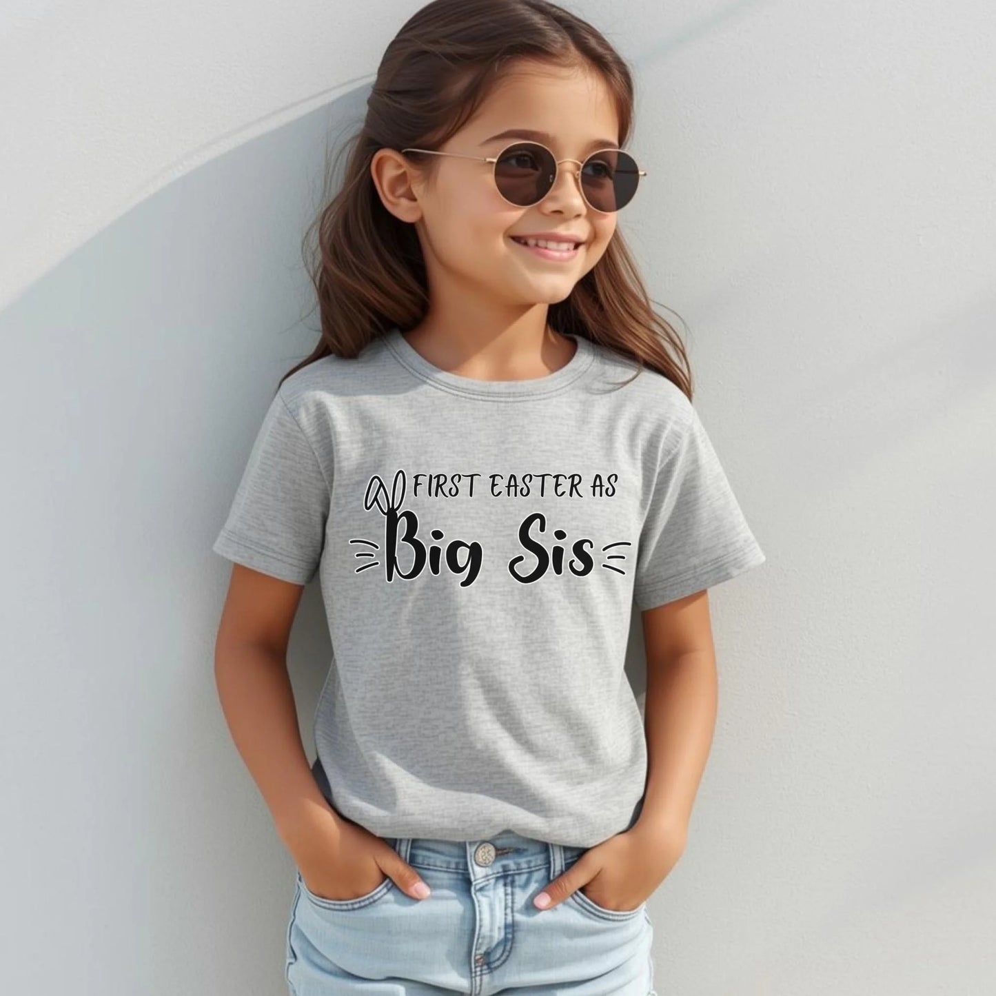 Girl modeling a grey “First Easter as Big Sis” youth t-shirt, styled for a fun and festive Easter family celebration.