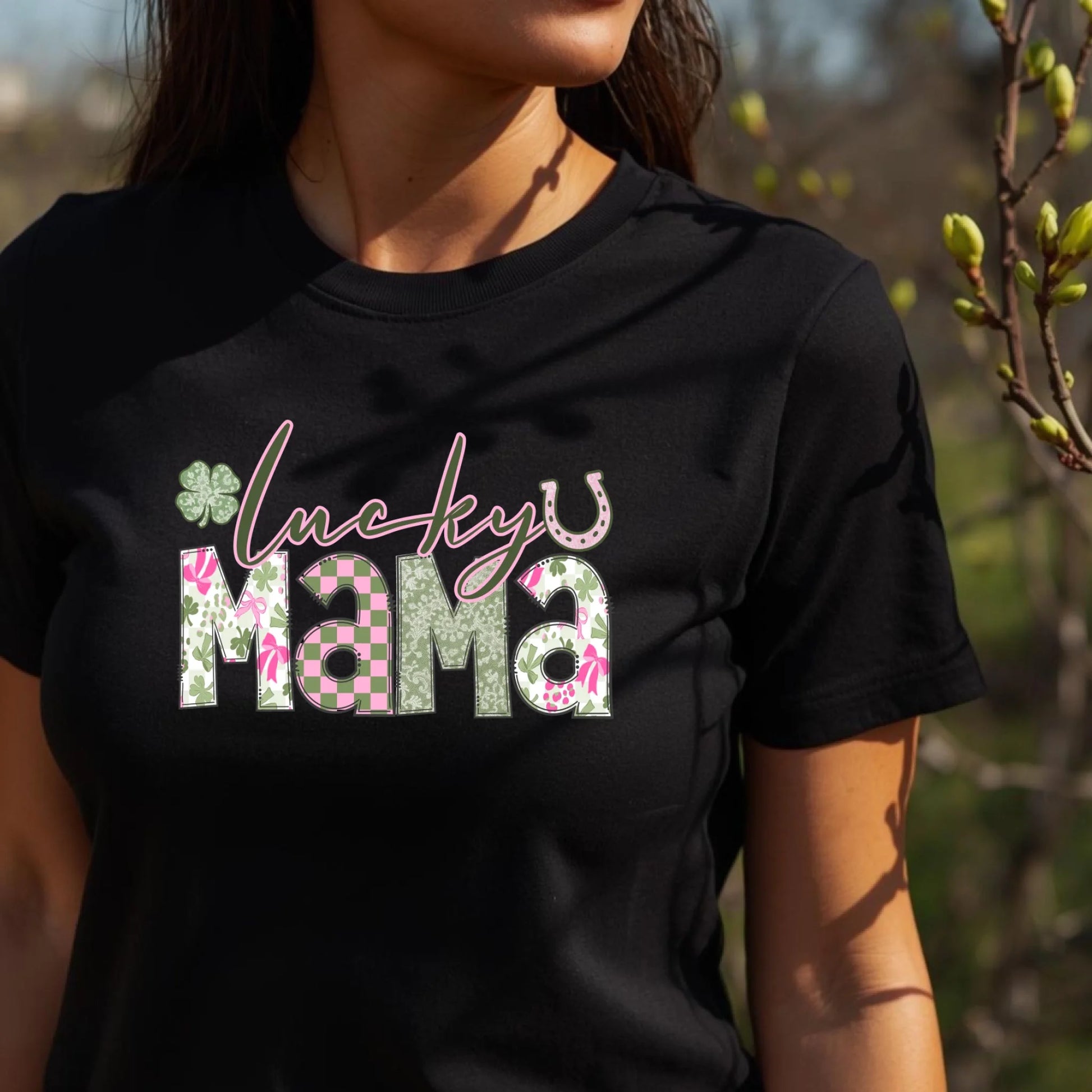 Person wearing a black t-shirt with 'lucky mama' text and floral design outdoors.