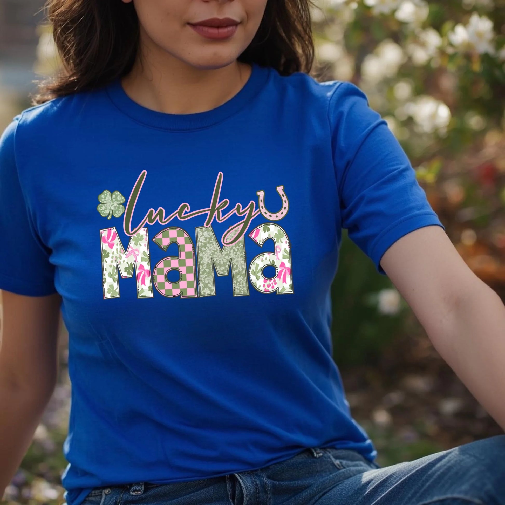 Person wearing a blue t-shirt with 'lucky mama' text and floral designs outdoors.