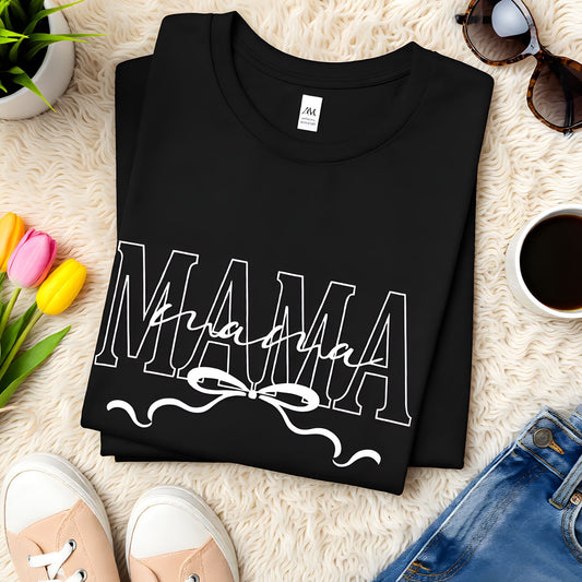 Folded black Bella Canvas Mama t-shirt featuring a minimalist script design with bow detail on a neutral flat lay background.