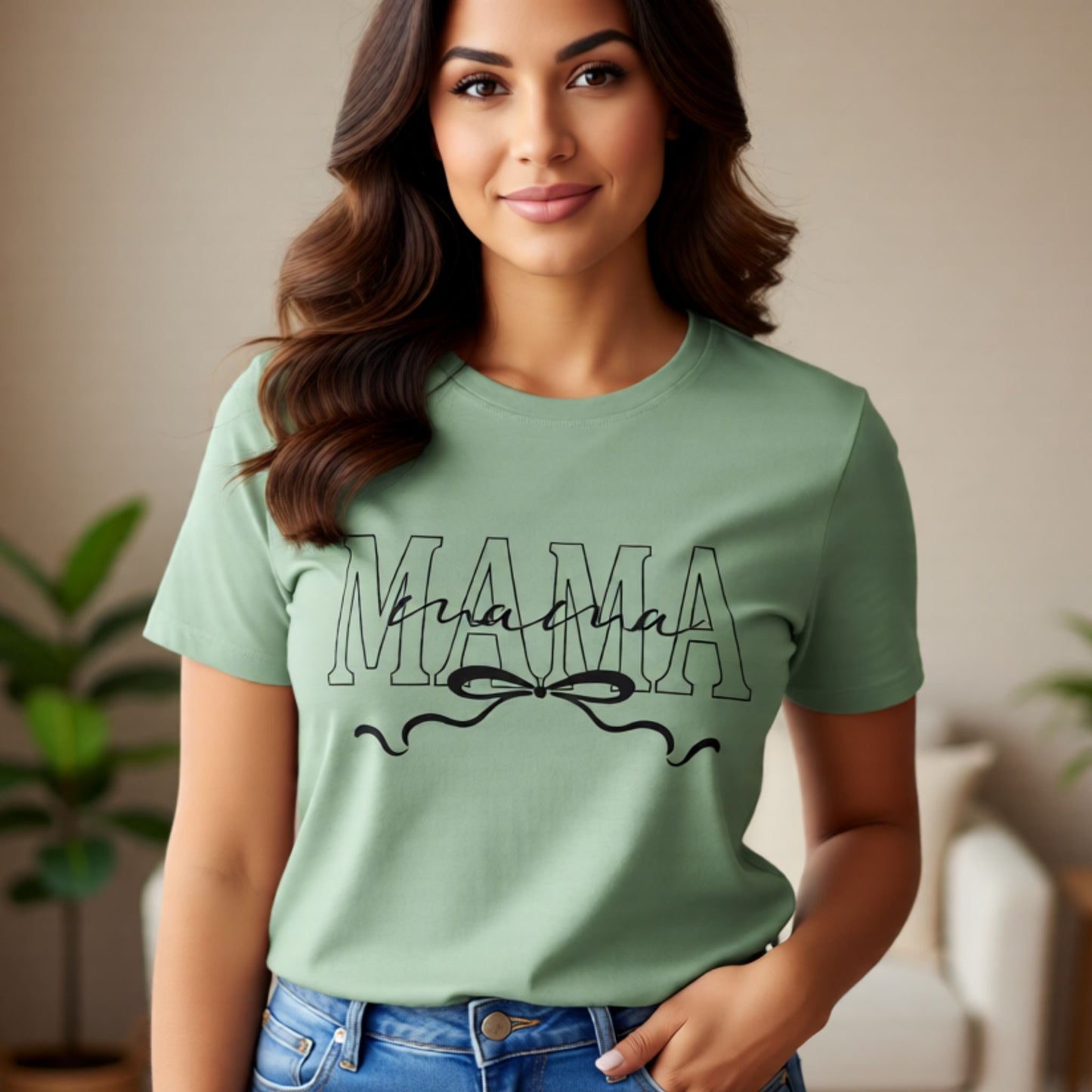 Model wearing a sage green Mama script t-shirt with bow detail, styled for everyday casual wear.