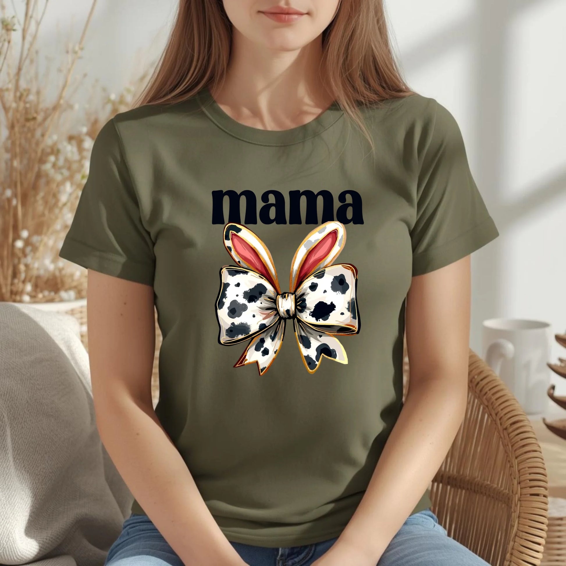 Woman wearing an olive green Bella + Canvas mama t-shirt with cow print bunny bow design, cozy spring outfit for Mother’s Day.