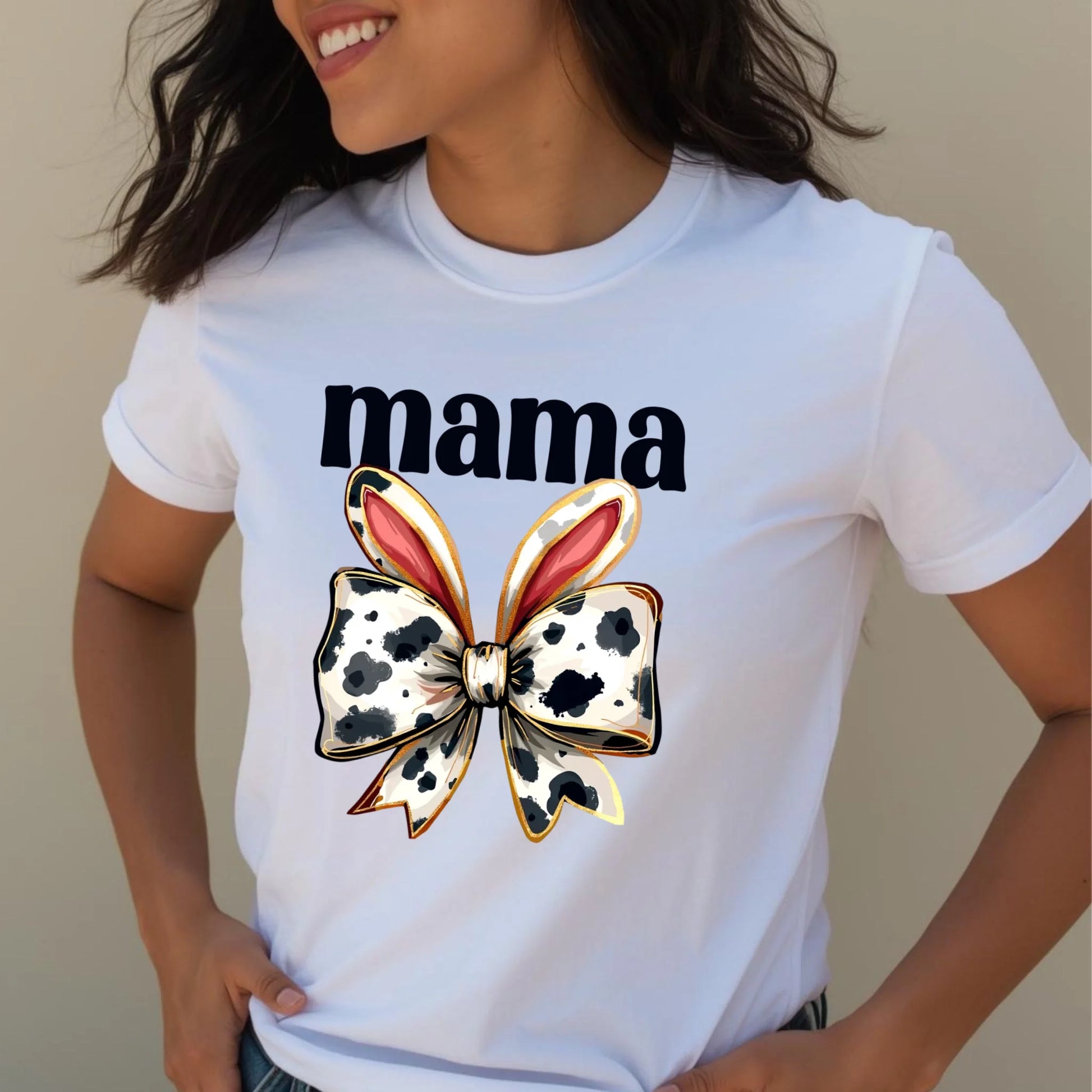 Close-up lifestyle photo of a woman wearing a white Bella + Canvas mama t-shirt with a cow print bunny bow graphic, casual spring fashion look.