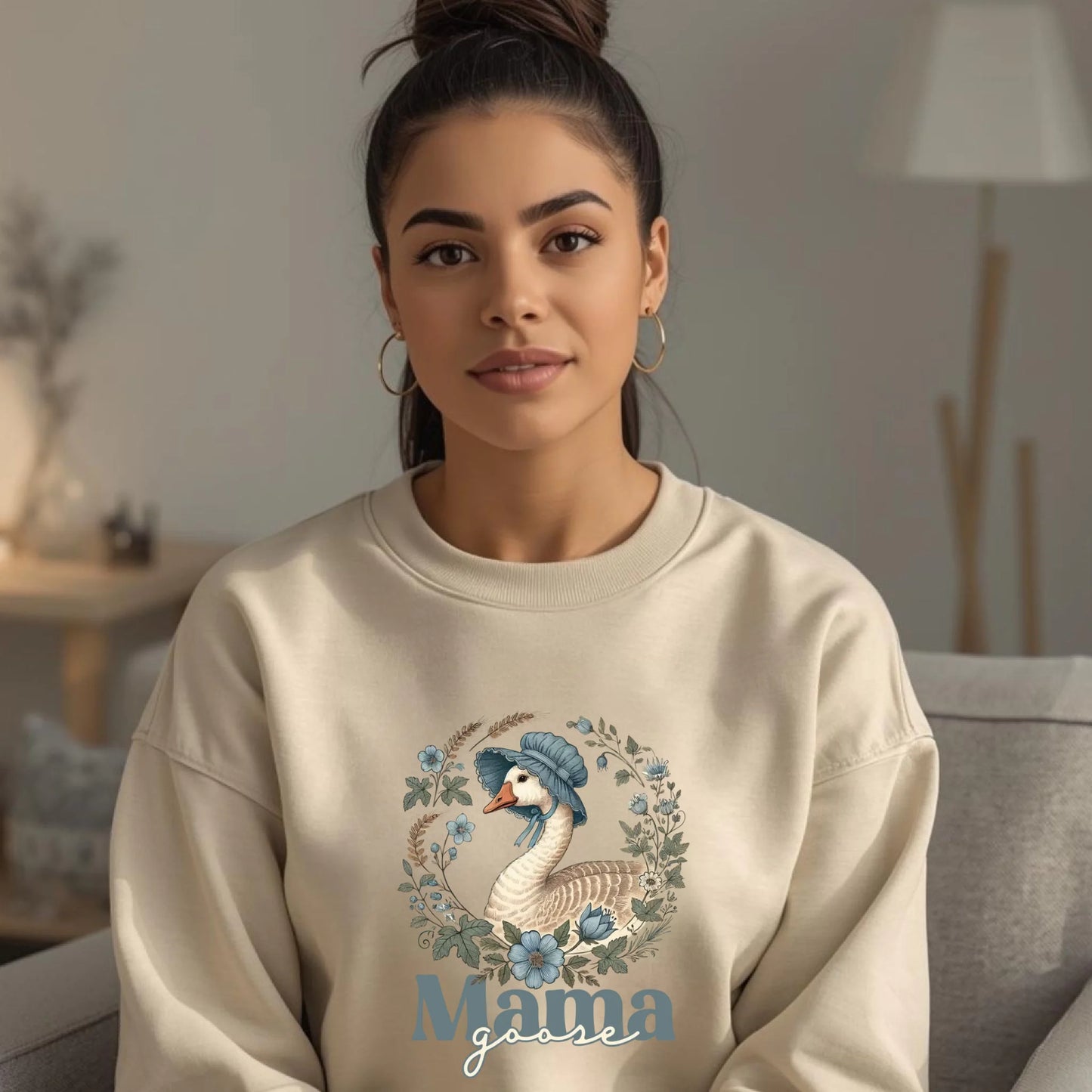 Woman wearing a light neutral Mama Goose floral crewneck sweatshirt indoors, styled for comfort with a soft goose and floral wreath design.