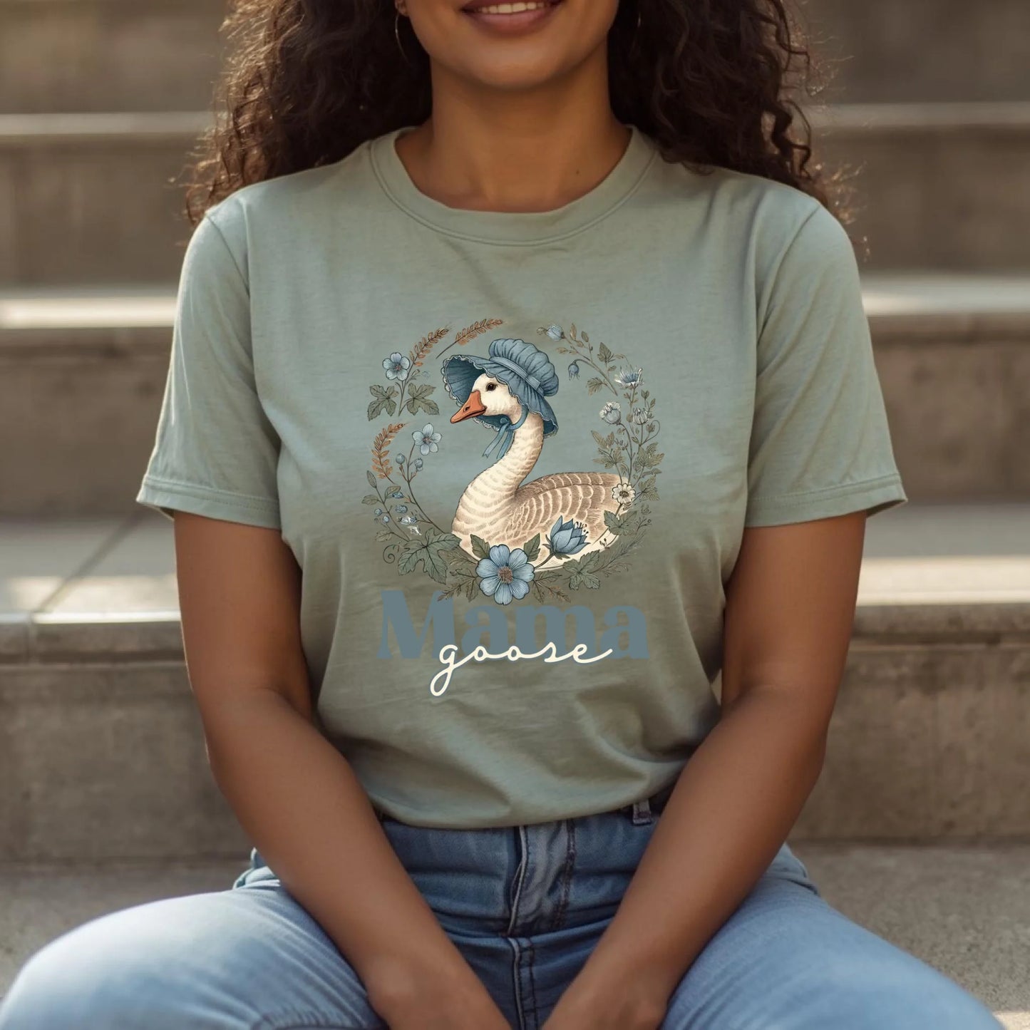 Person wearing a t-shirt with a goose graphic and 'Mama goose' text, sitting on steps.