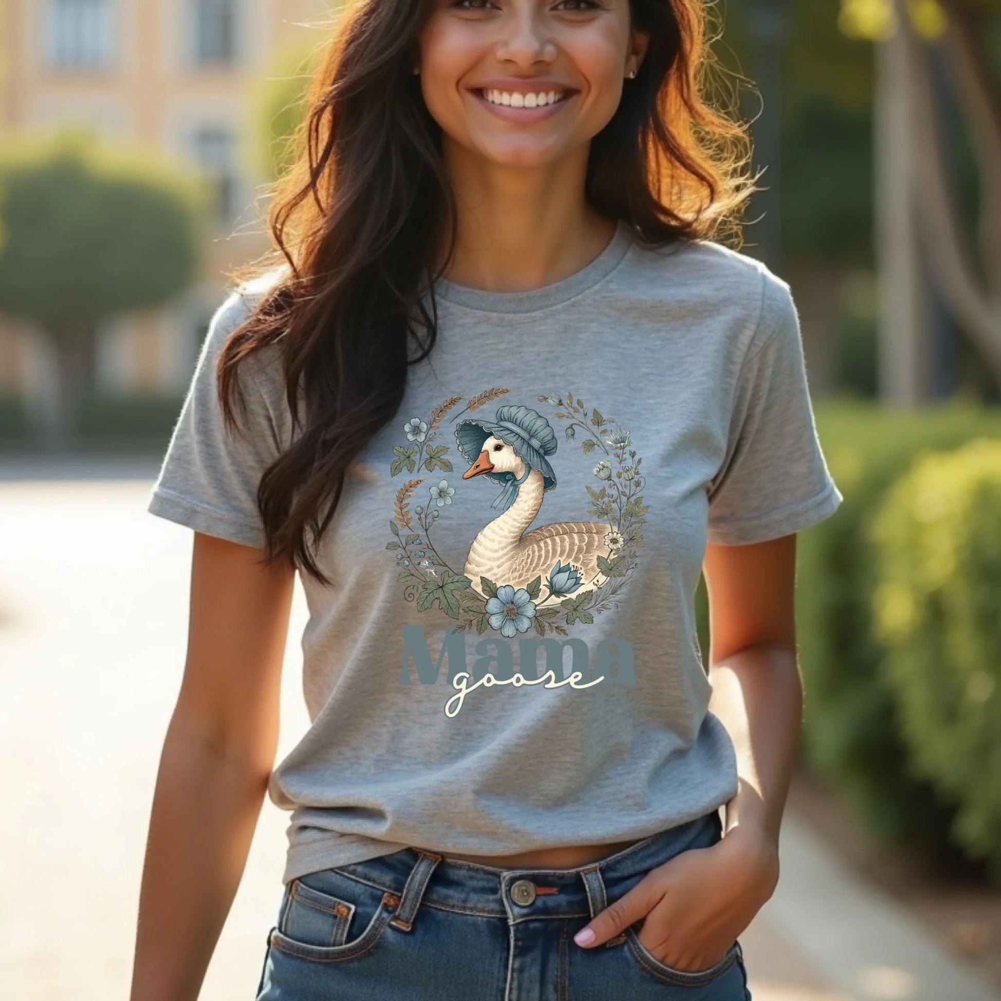 Lifestyle photo of a woman wearing a heather gray Mama Goose floral t-shirt, showcasing a vintage-inspired goose illustration with soft blue flowers.