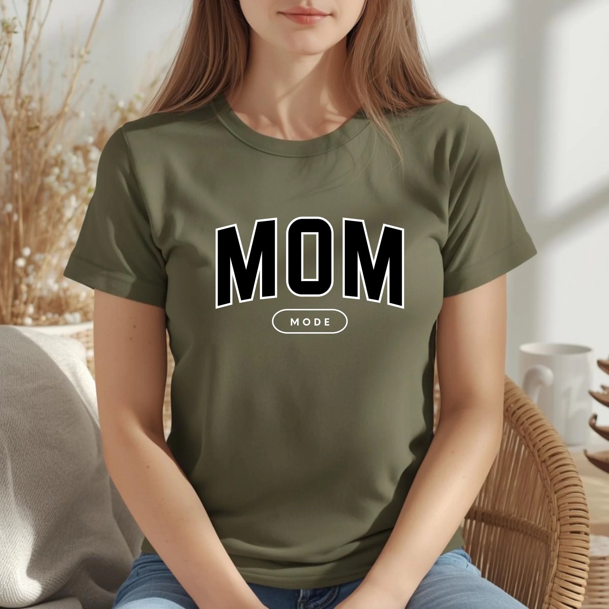 Person wearing a military green t-shirt with 'MOM MODE' text in a casual setting.