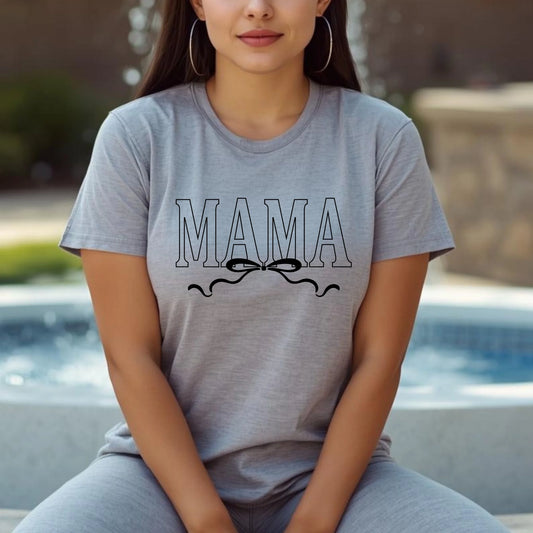 Woman wearing a gray t-shirt with 'MAMA' printed on it, sitting by a pool.