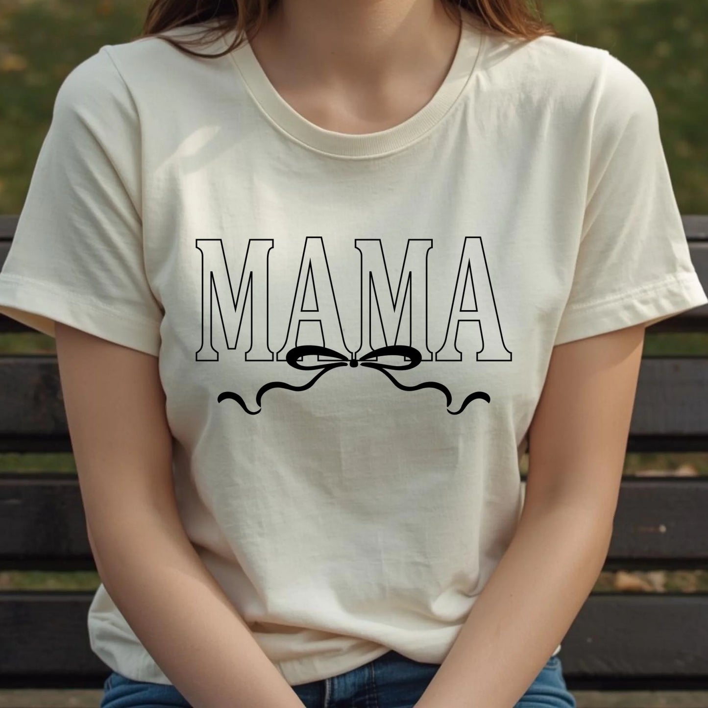 Person wearing a white t-shirt with 'MAMA' text and a bow graphic.